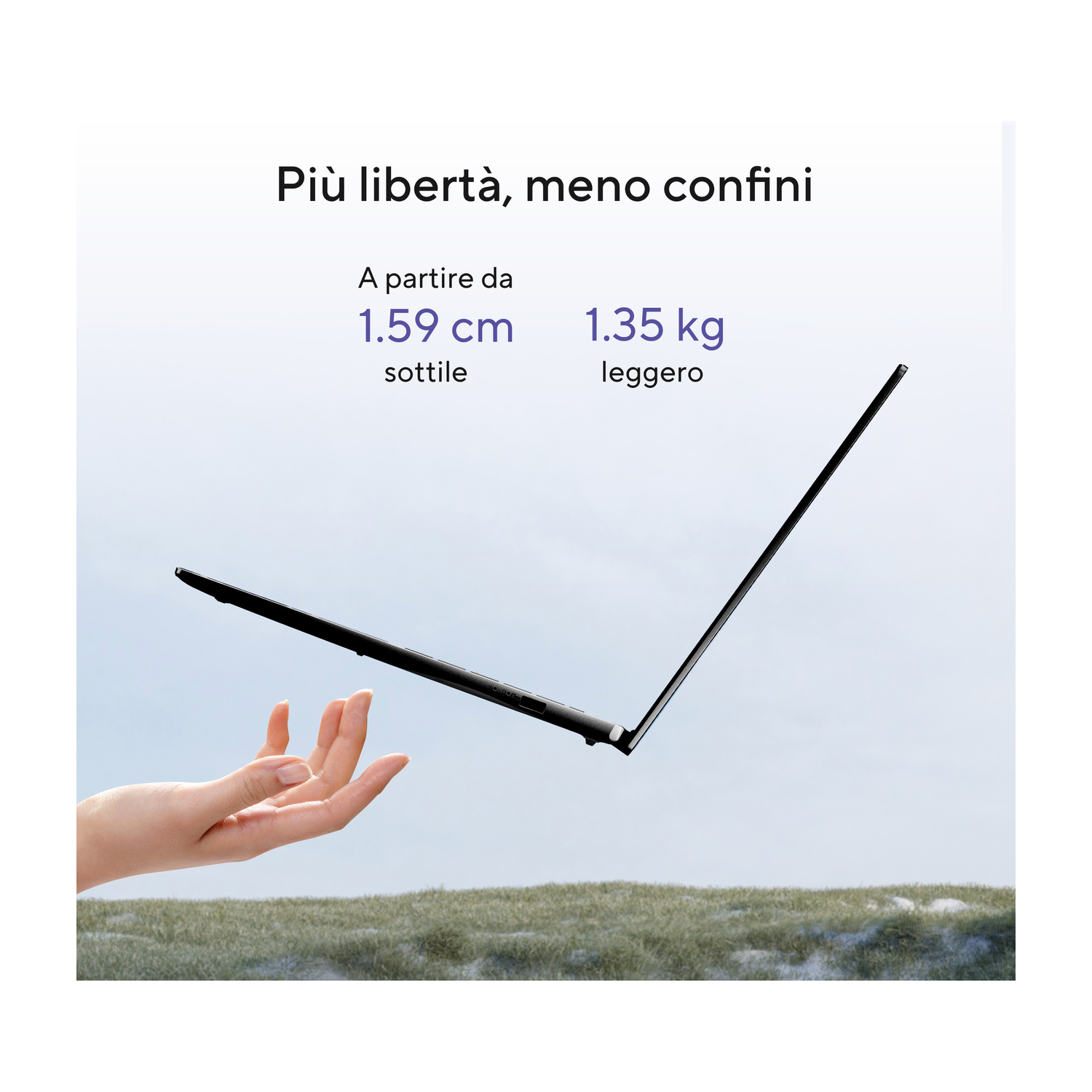 Una mano tiene un laptop nero sottile contro un cielo azzurro sopra l'erba.