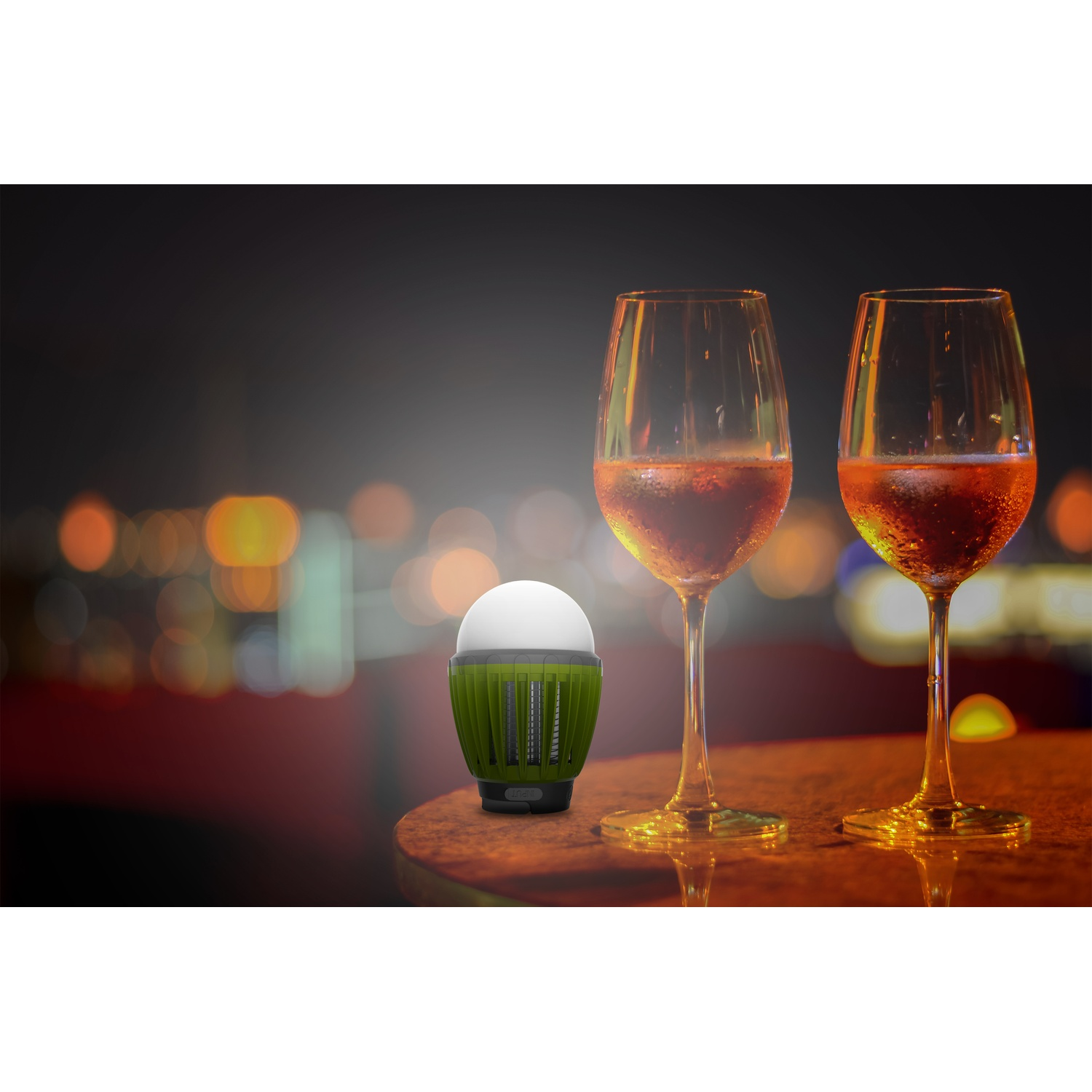 Una luce verde e due bicchieri di vino su un tavolo di legno di notte.