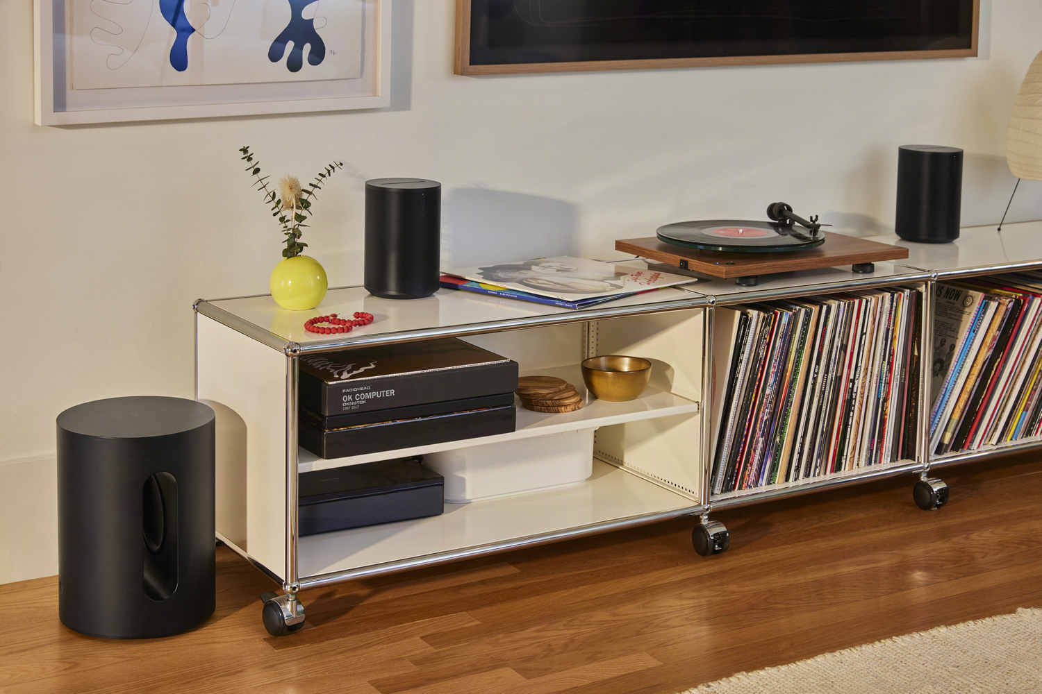 Tocadiscos negro en un estante con vinilos y altavoces.