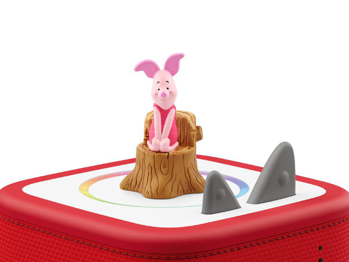 Ein Spielzeug von Piglet sitzt auf einem Baumstumpf neben grauen Haifischflossen.