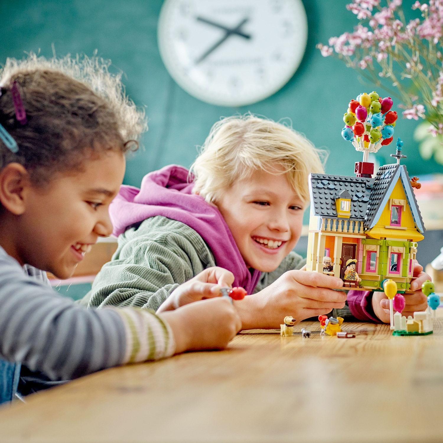 Two children build a Lego house with balloons, dogs, and figures.