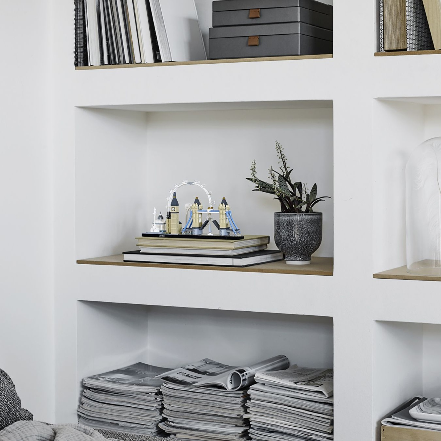 A London souvenir model sits on a stack of books, with a potted plant beside it.
