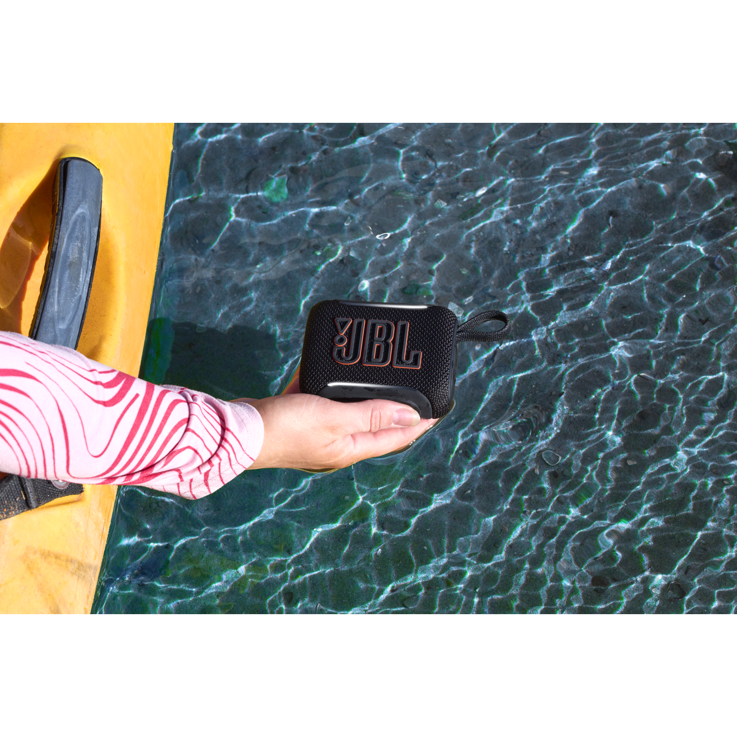 Black JBL speaker held over dark water.