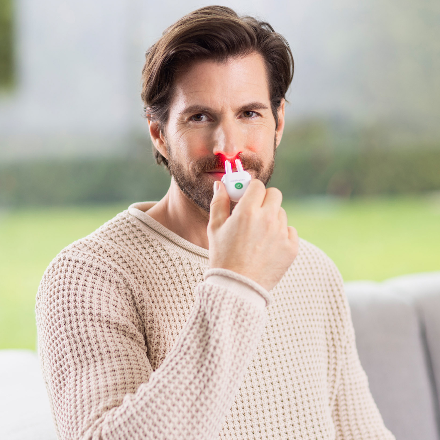 Man with a nasal light therapy device, showing red lights on his nose.