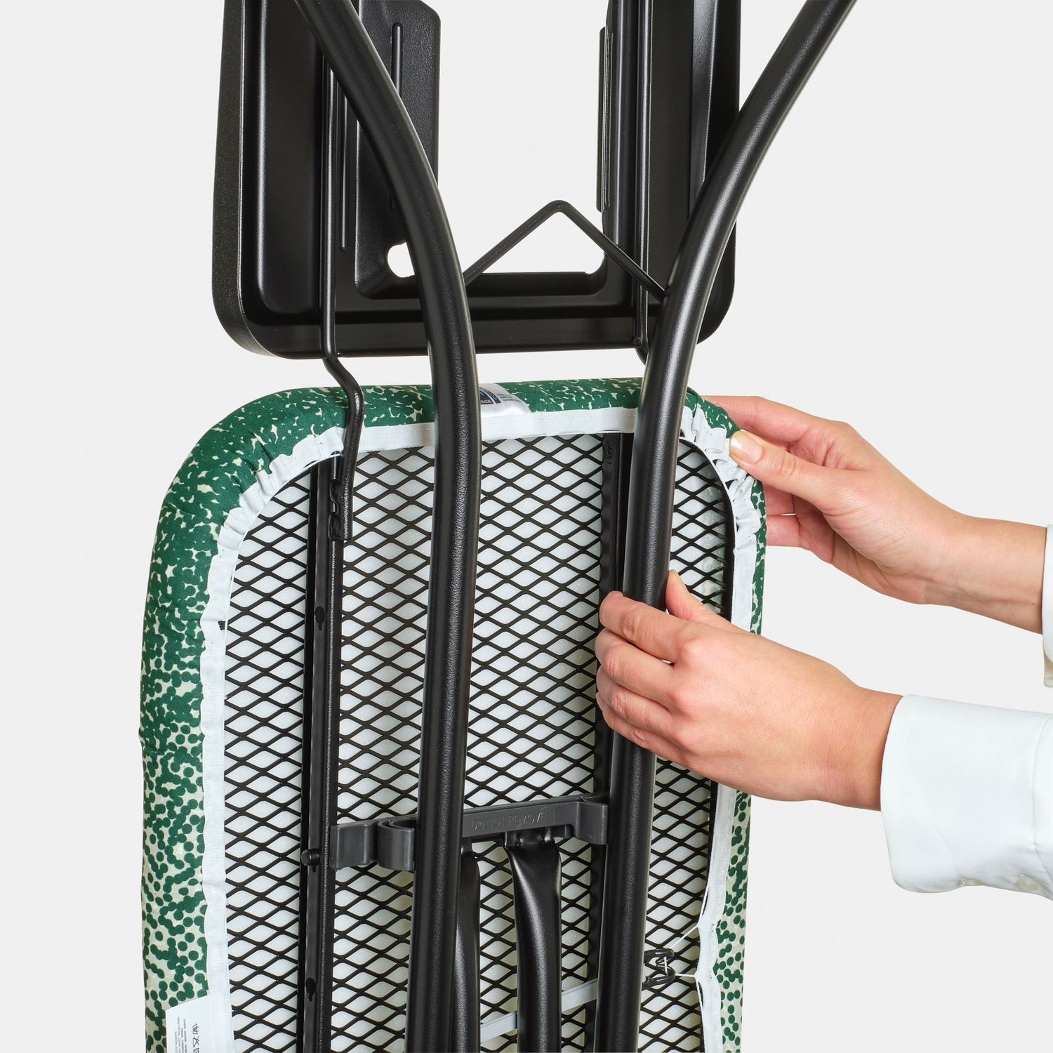 Hands place an ironing board with green cover into a wall mount.