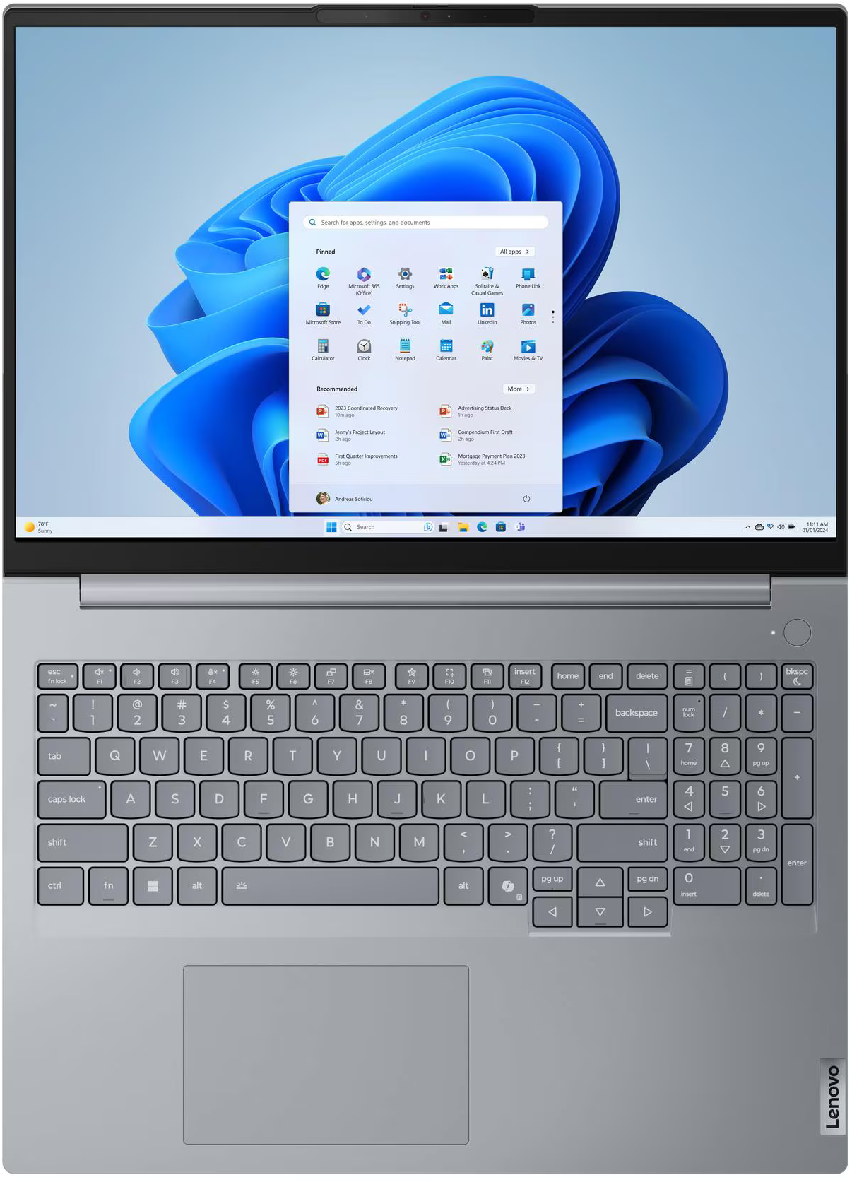 Laptop Windows 11 Start menüvel és billentyűzettel. A képernyőn kék hullámok láthatók.