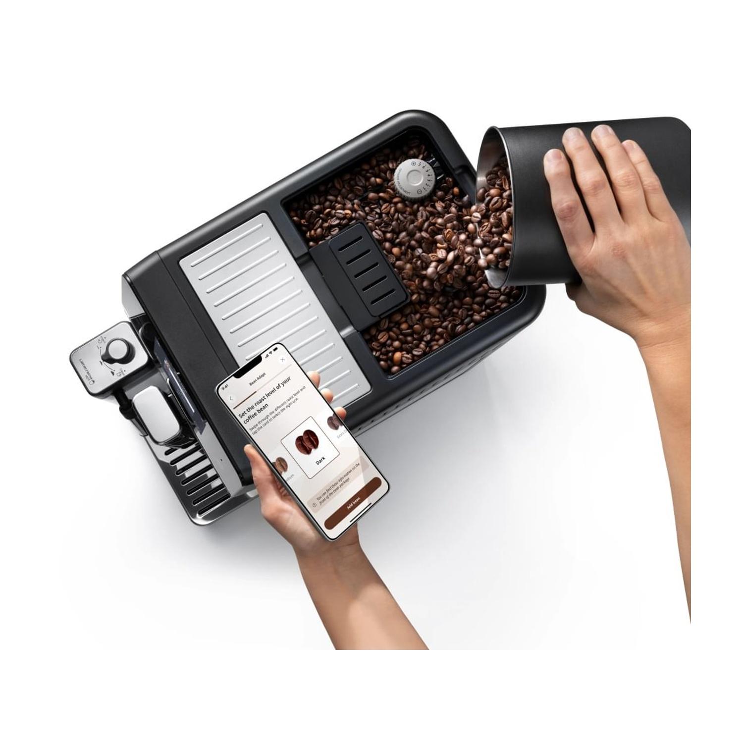 Una mano versa chicchi di caffè in una macchina da caffè, un'altra tiene uno smartphone.