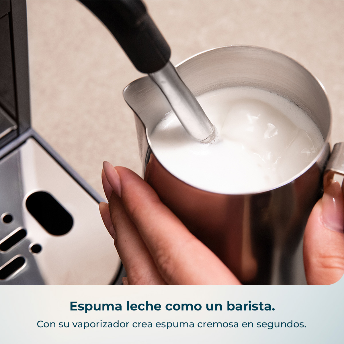 Una mano sostiene una jarra de leche mientras un vaporizador la espumea.