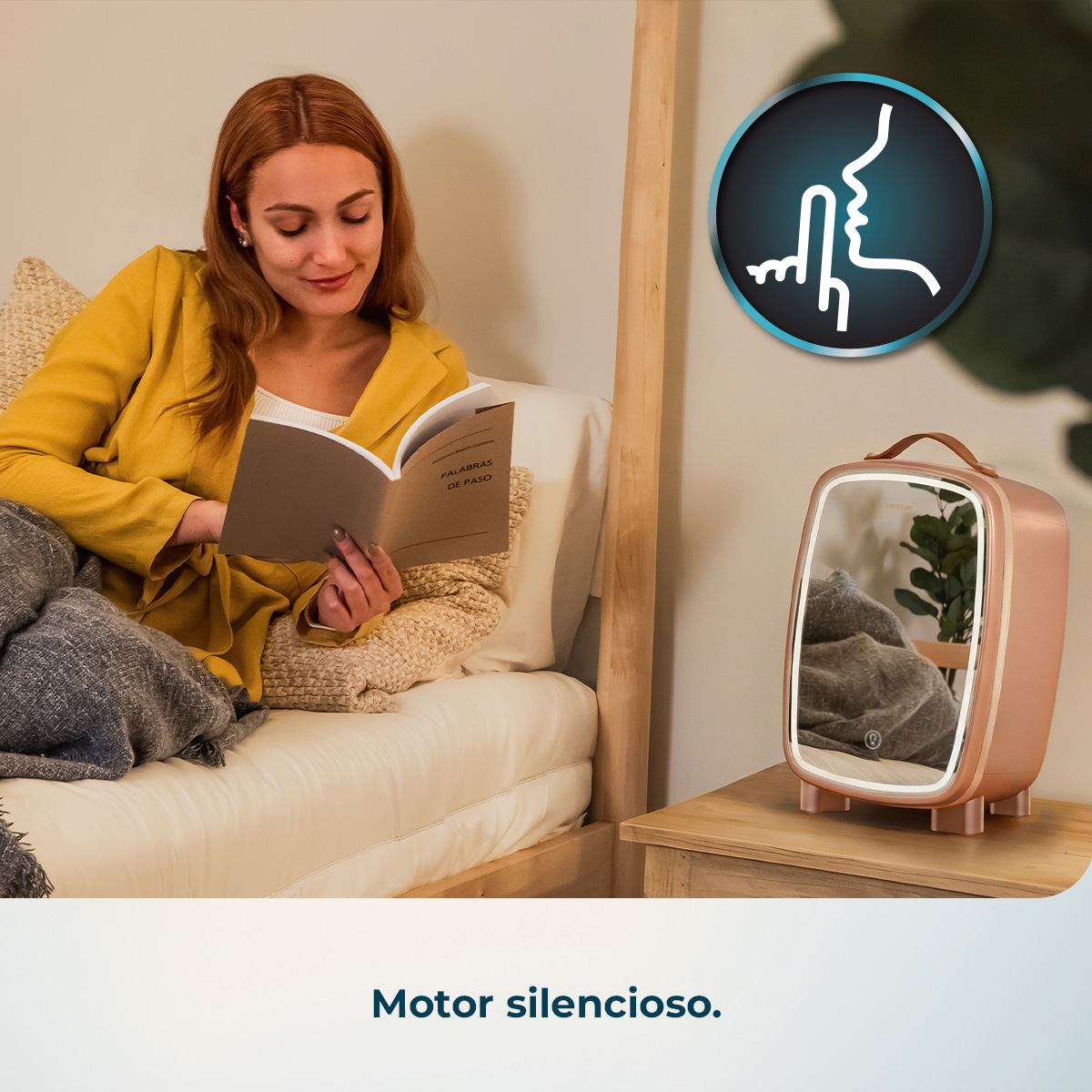 Mujer leyendo un libro, con un pequeño espejo de tocador en una mesita de noche.