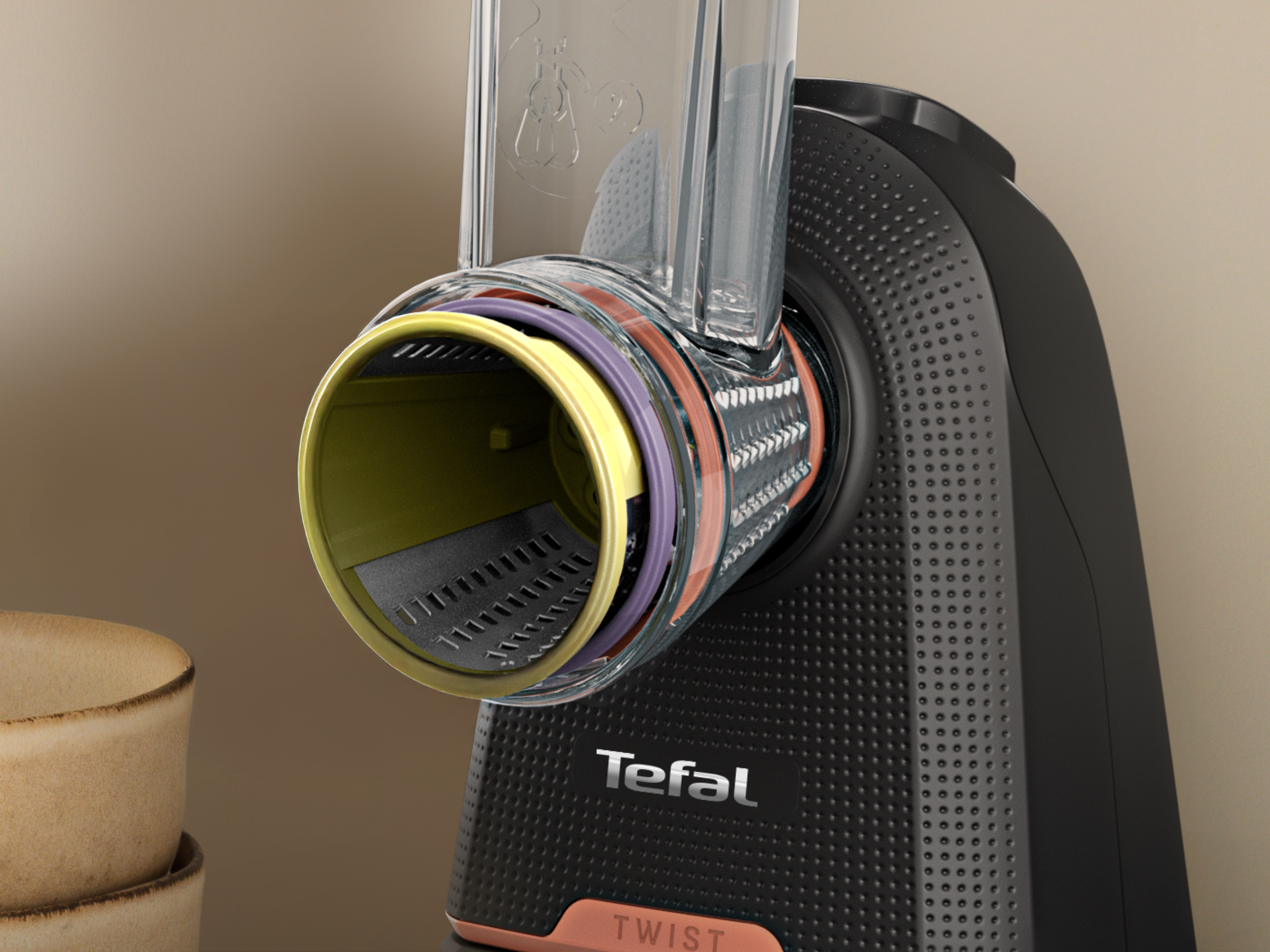 Fekete Tefal reszelő közeli képe, átlátszó toldattal és színes gyűrűkkel.