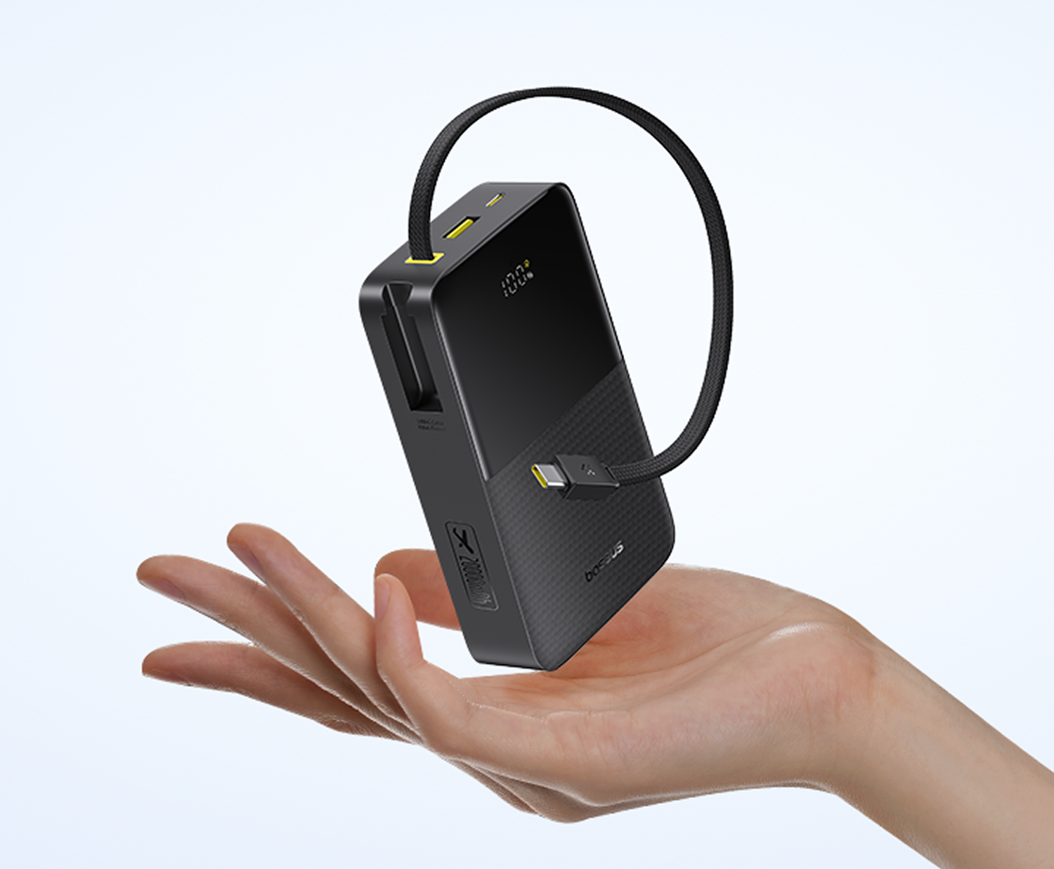 Batería externa negra con cable flota sobre mano, indicador de carga muestra 100%.