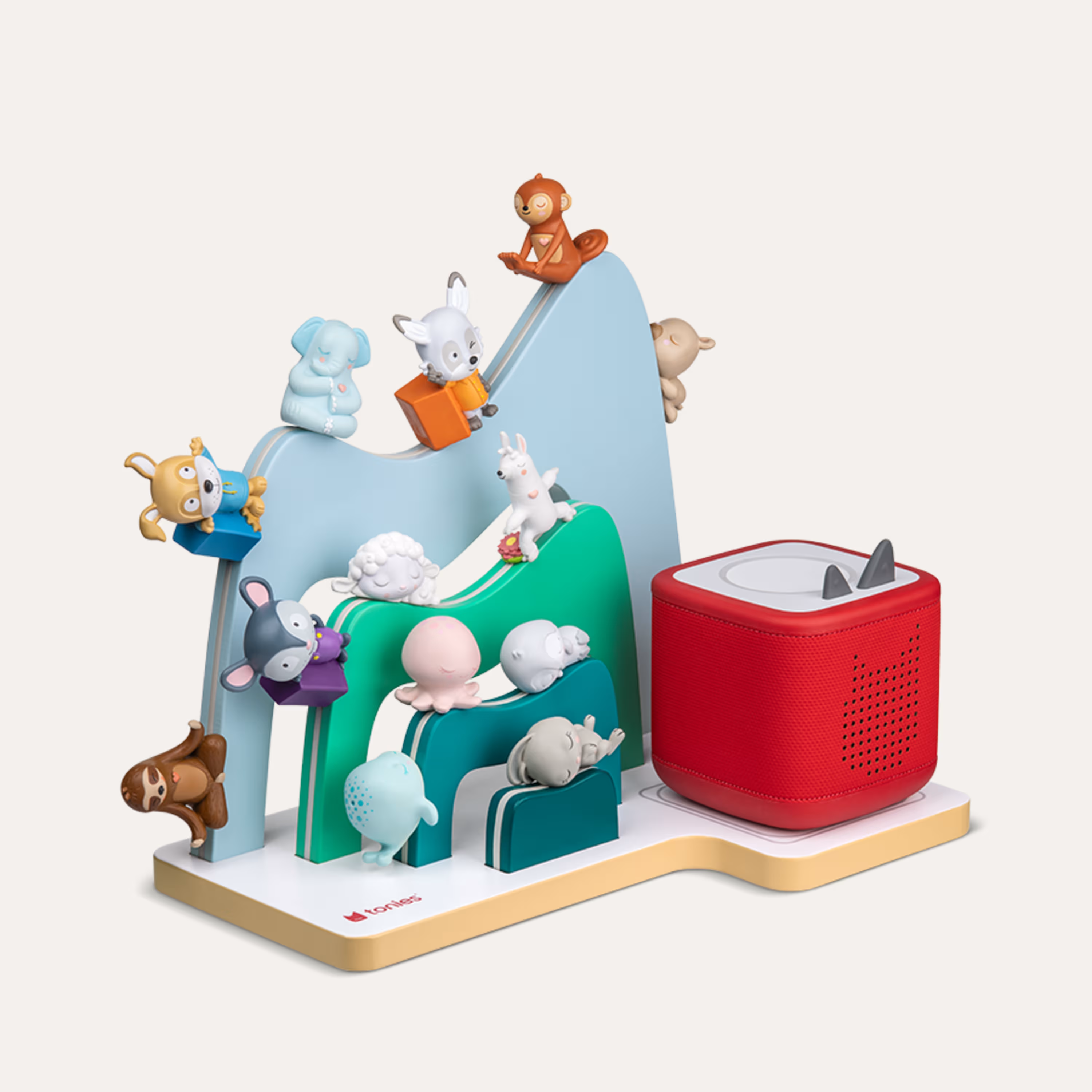 Bunte Tierfiguren auf einer Spielzeugtoniebox und einer Bergkulisse.