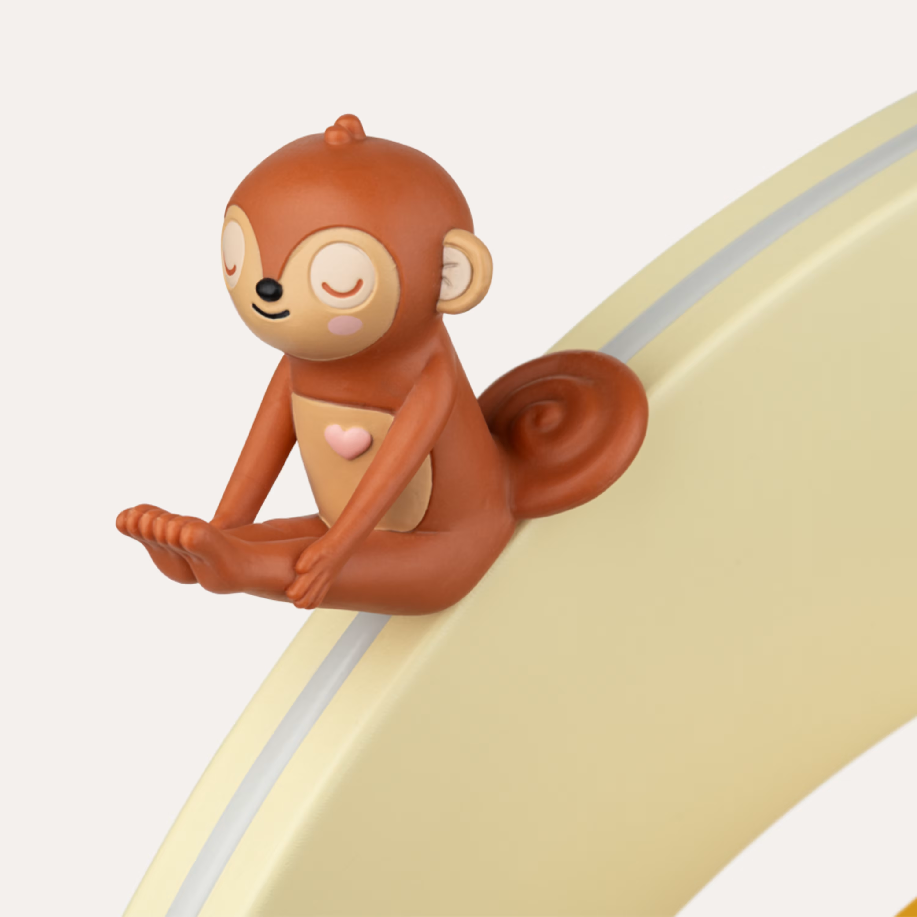 Eine braune Eichhörnchenfigur sitzt auf einer gelben Rutsche mit einem rosa Herz auf dem Bauch.