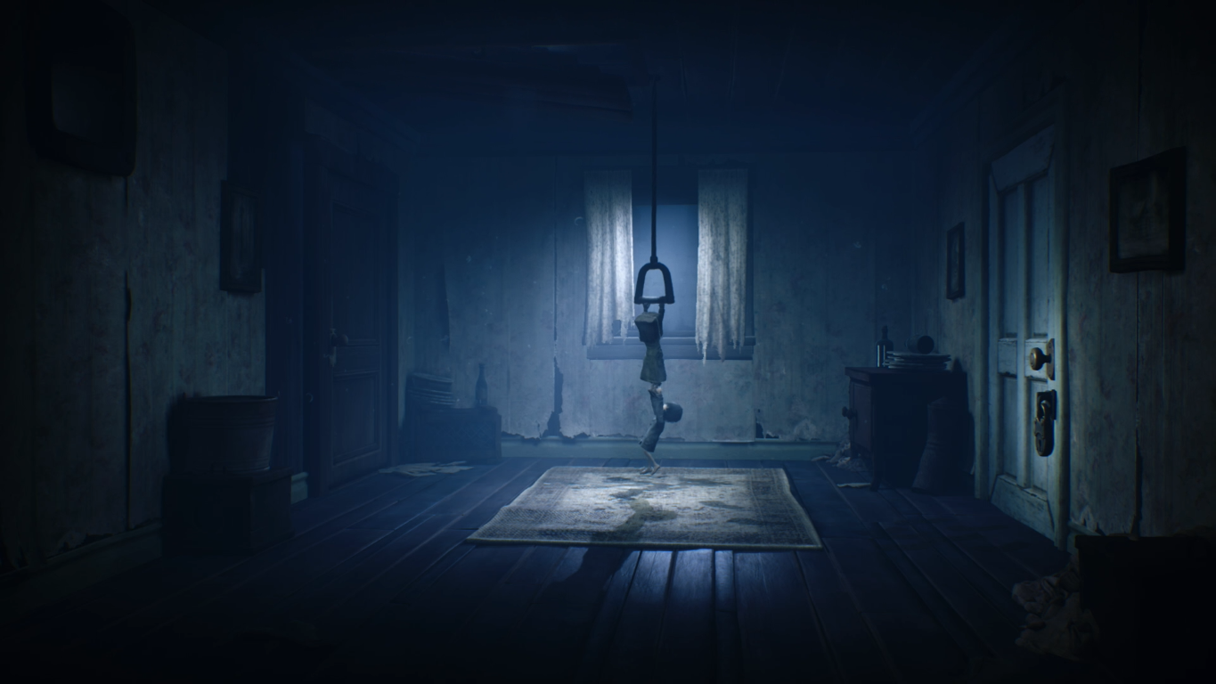 Dziecko wisi na haku pod oknem w ciemnym pokoju.