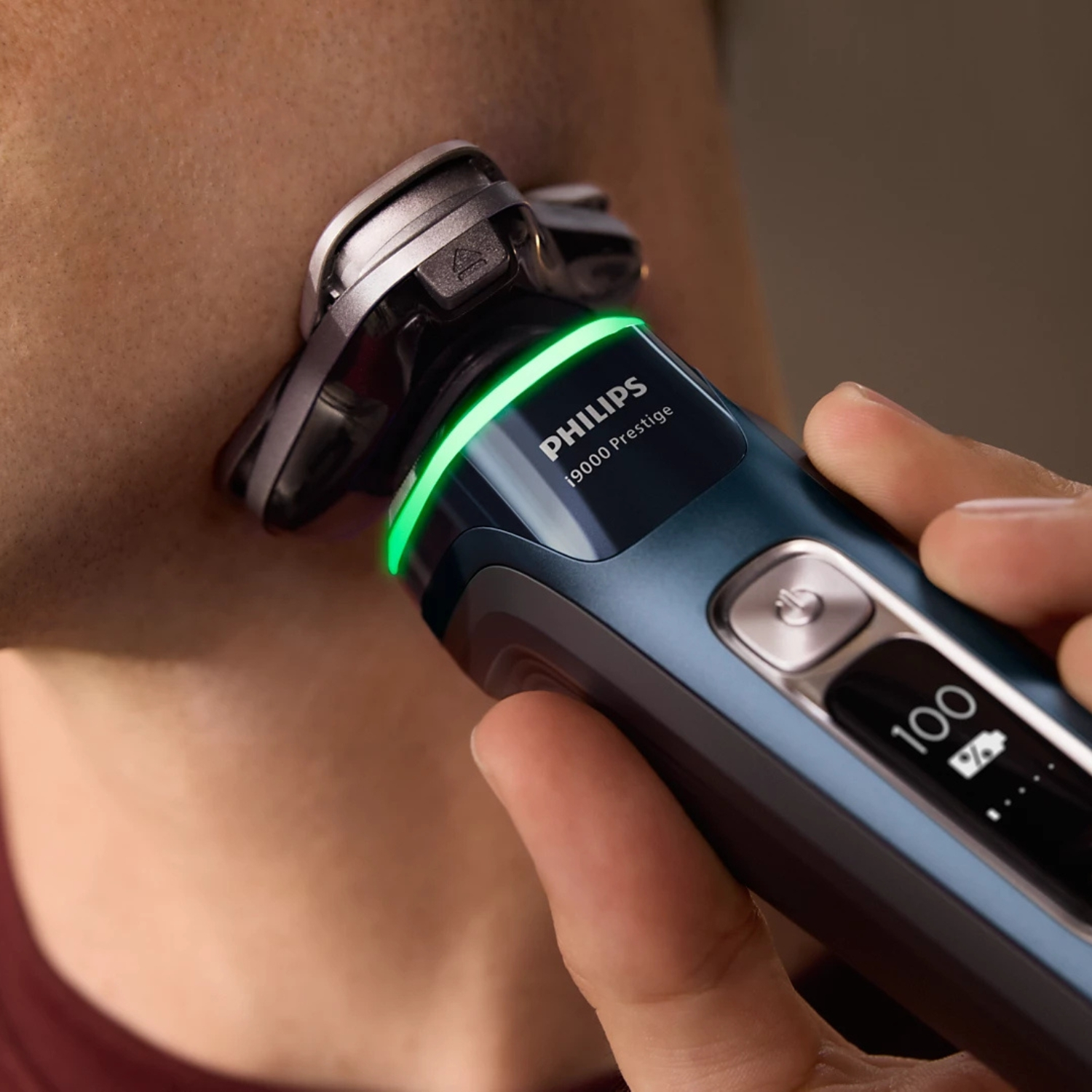 Afeitadora eléctrica Philips con luz verde usada en la cara de un hombre.