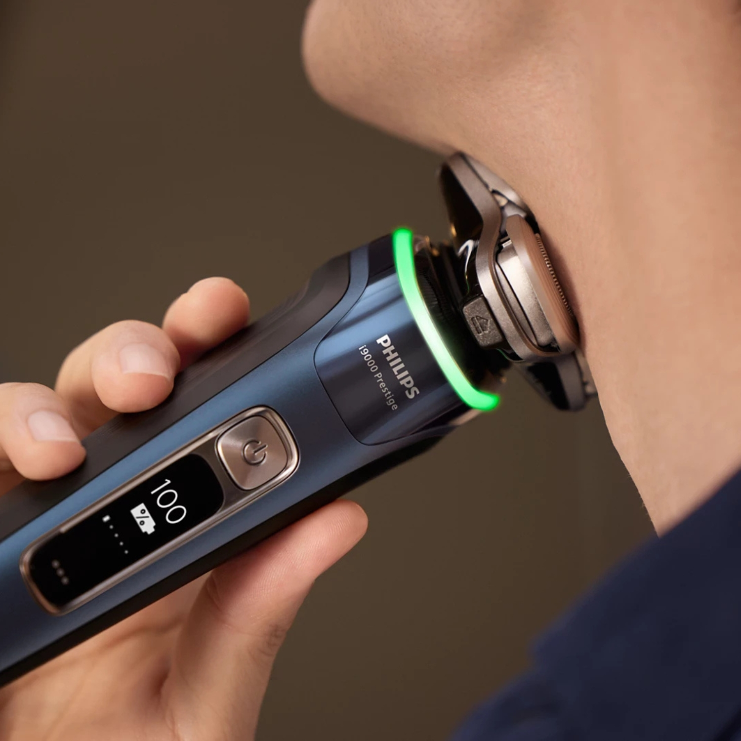 Un hombre se afeita el cuello con una afeitadora Philips azul que muestra carga completa.