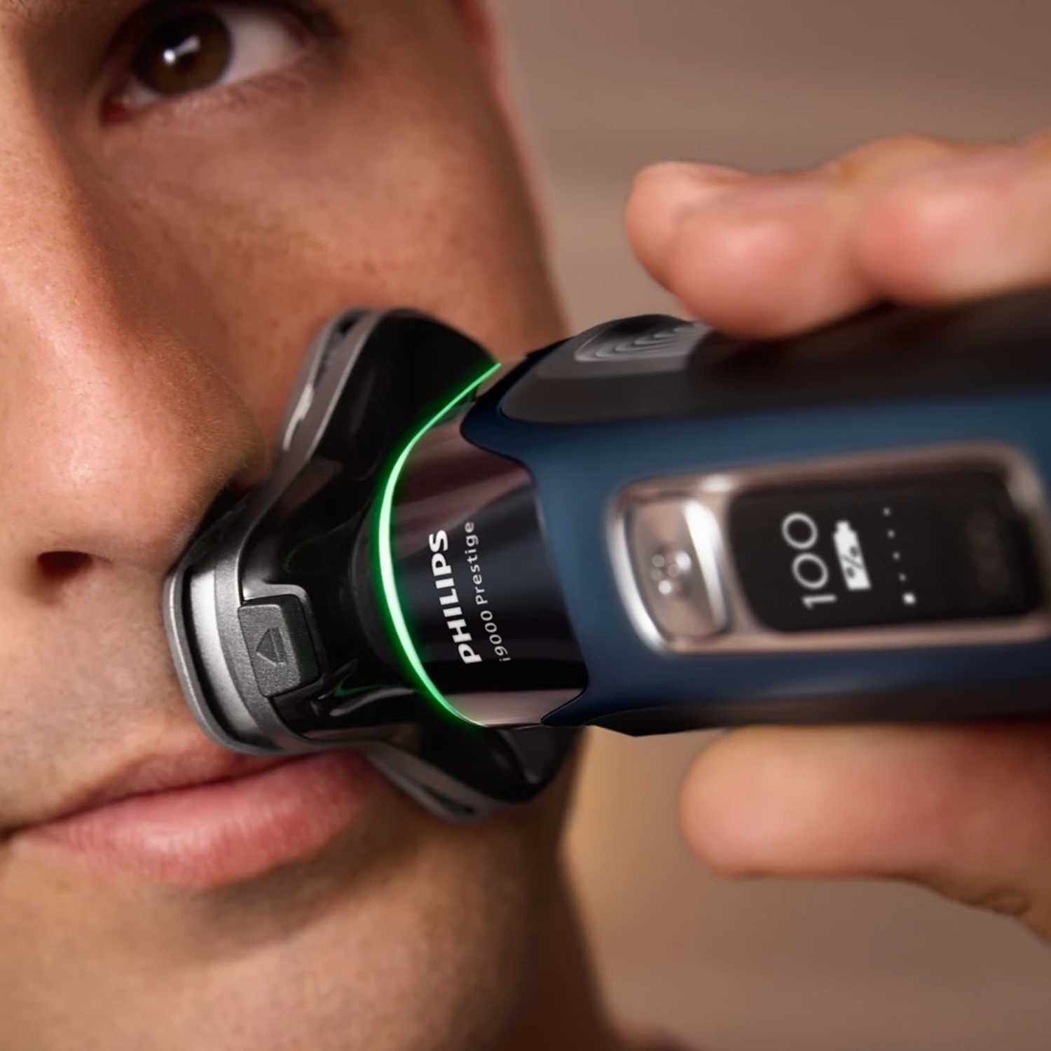 Hombre se afeita la cara con una afeitadora Philips azul con luz verde.