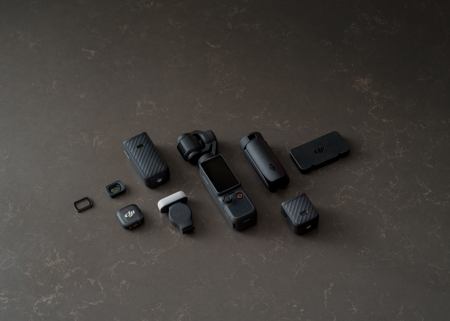 Varios accesorios negros para cámara DJI Osmo están dispuestos sobre una encimera oscura.