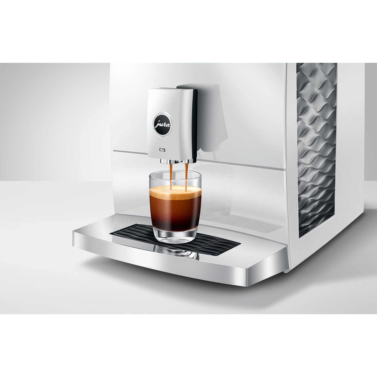 Een witte koffiemachine zet espresso in een glas op een chromen lekbak.