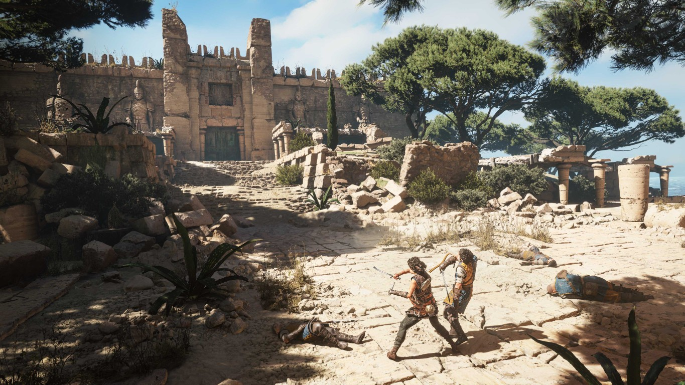 Dwóch wojowników walczy przed starożytną ruiną, kilku leży na ziemi.