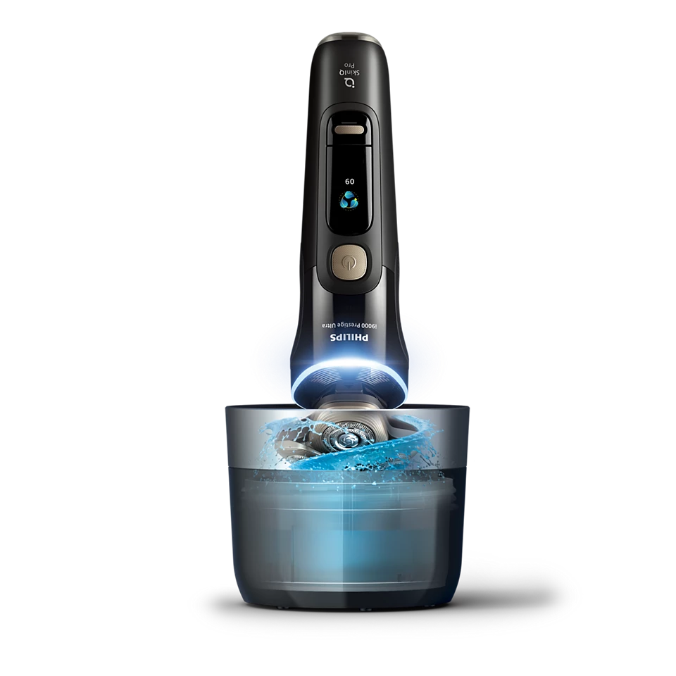 Una afeitadora Philips negra sobre un recipiente con agua azul y salpicaduras.