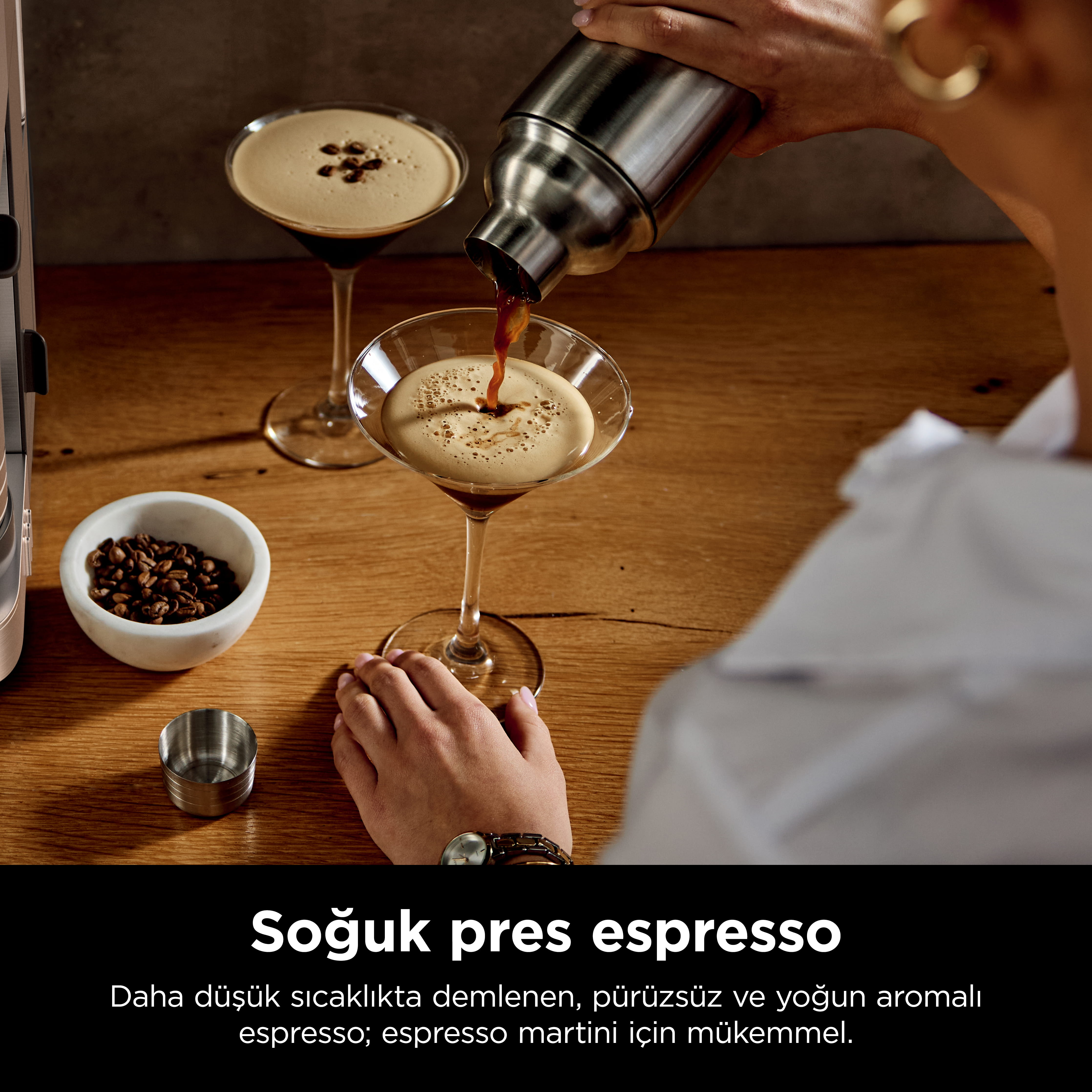 Espresso bir bardağa dökülüyor. Yakında kahve çekirdekleri var.