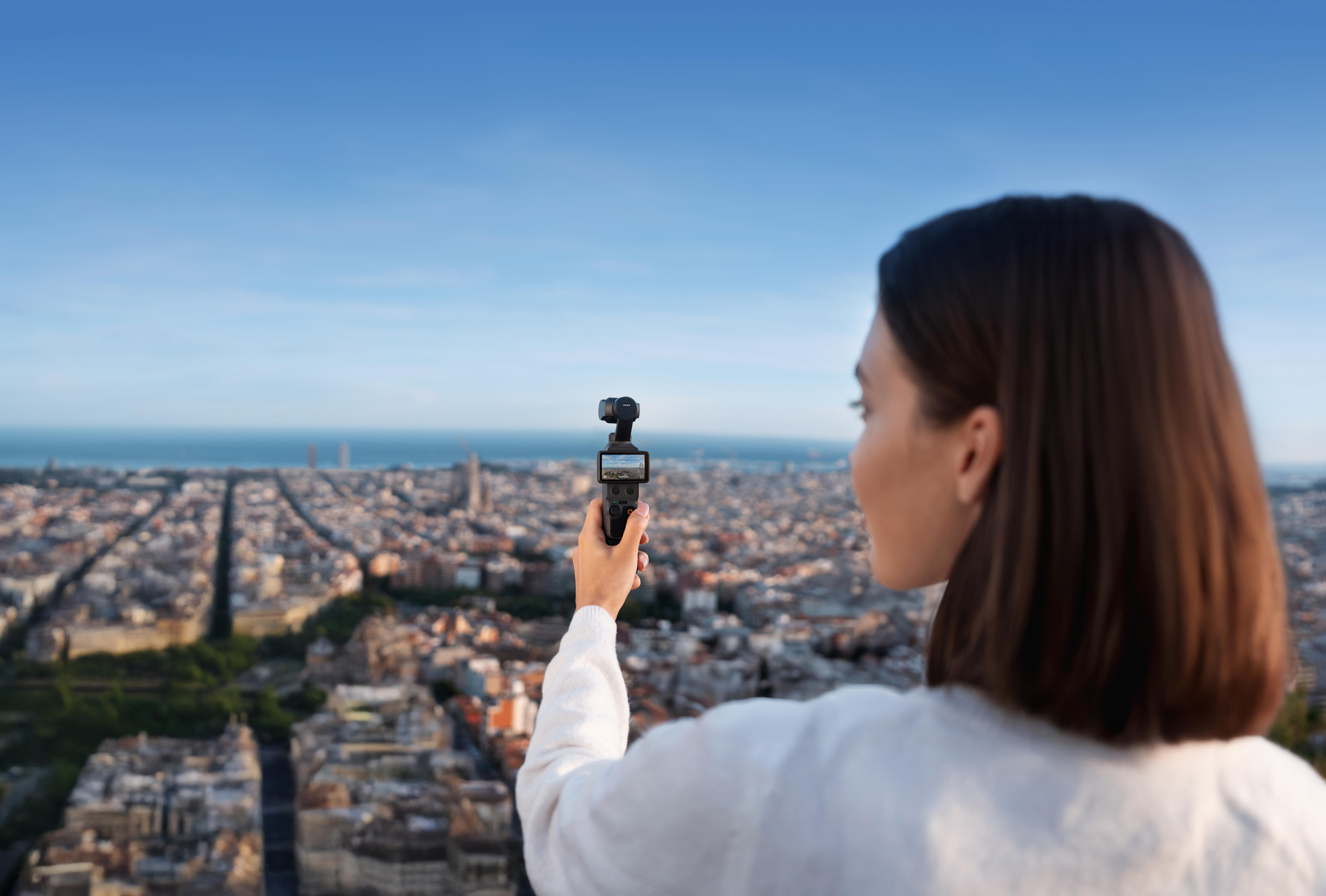 Eine Frau filmt mit einem Gimbal eine Stadtlandschaft bei Tag.