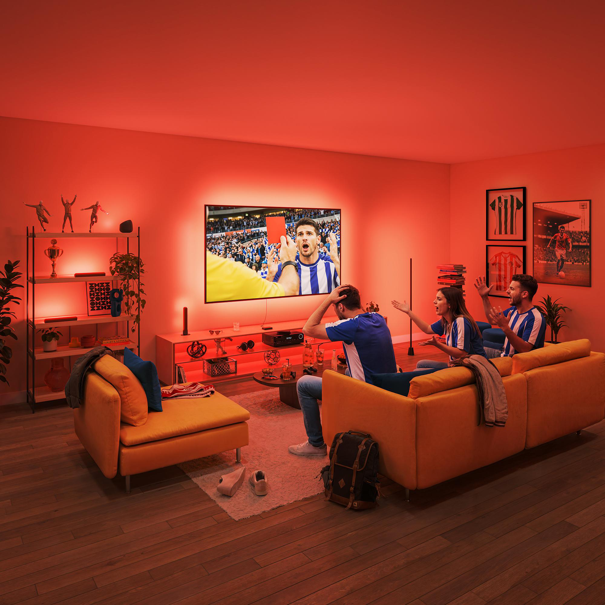 Fans in blauen Trikots schauen Fußball, einer zeigt eine rote Karte.