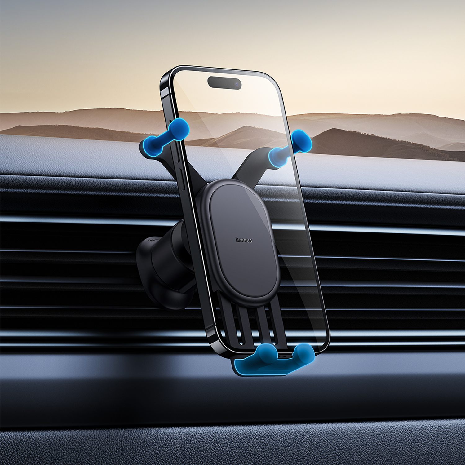 Soporte negro para teléfono con agarres azules sujeta un smartphone en una rejilla de coche. Montañas de fondo.