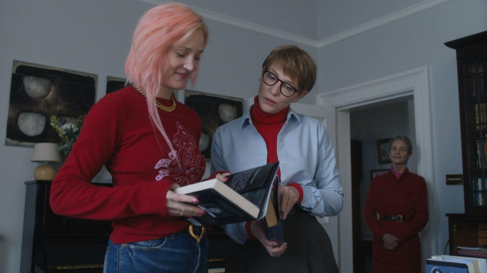 Zwei Frauen mit Büchern, eine dritte Frau steht im Hintergrund.