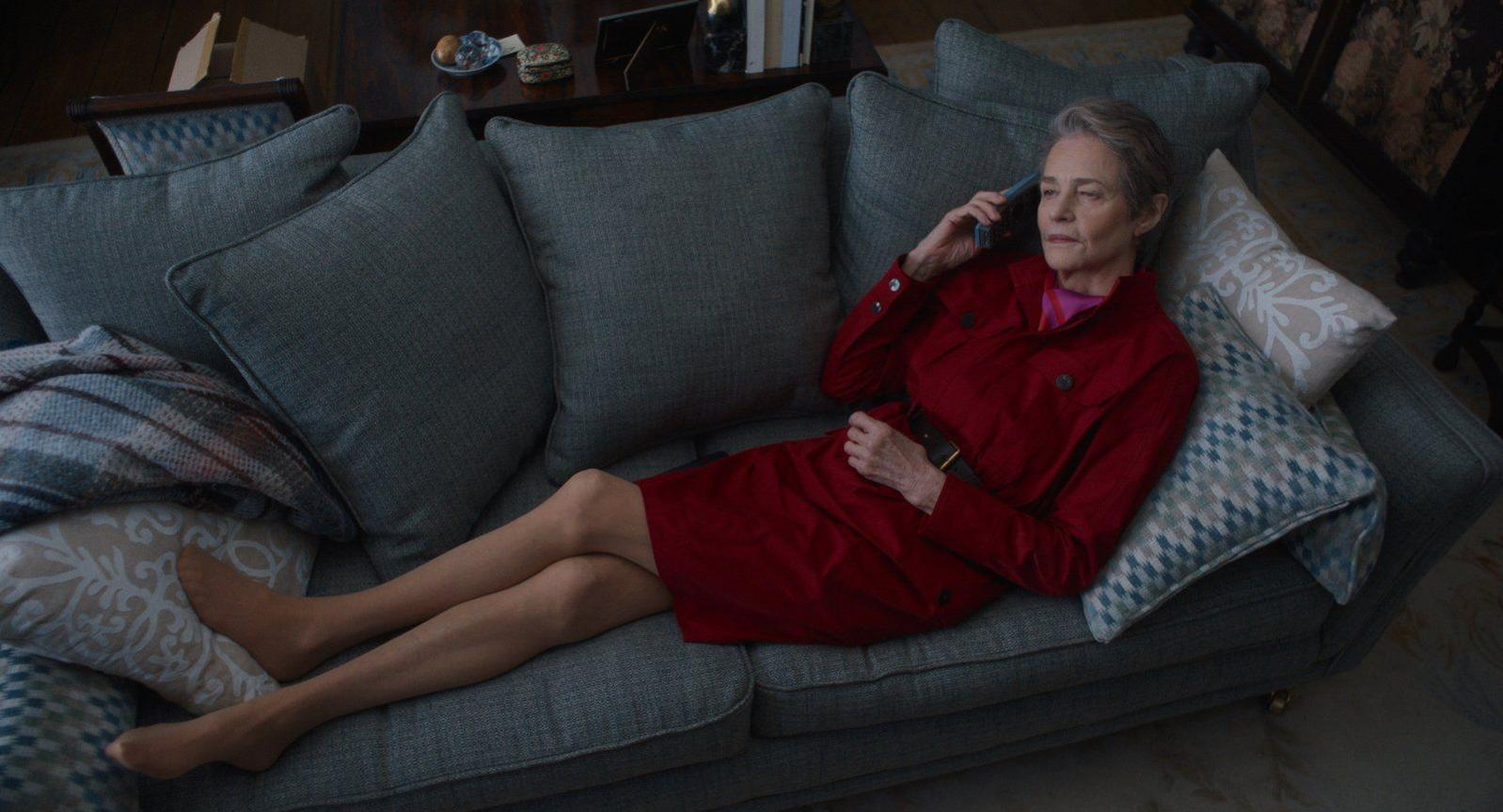 Eine Frau in einem roten Kleid telefoniert auf einem Sofa.