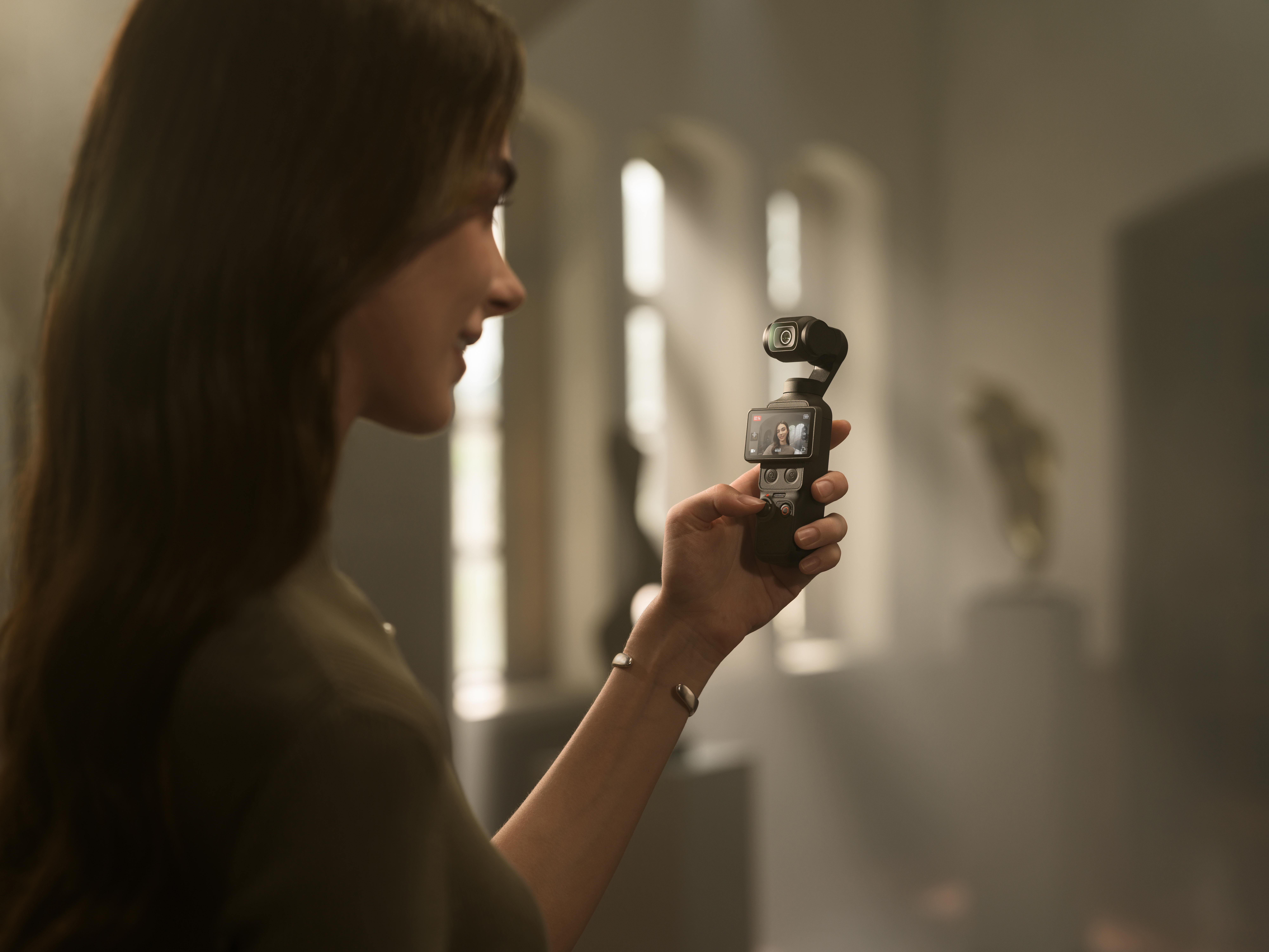 Eine Frau hält einen schwarzen Gimbal-Stabilisator mit Kamera.