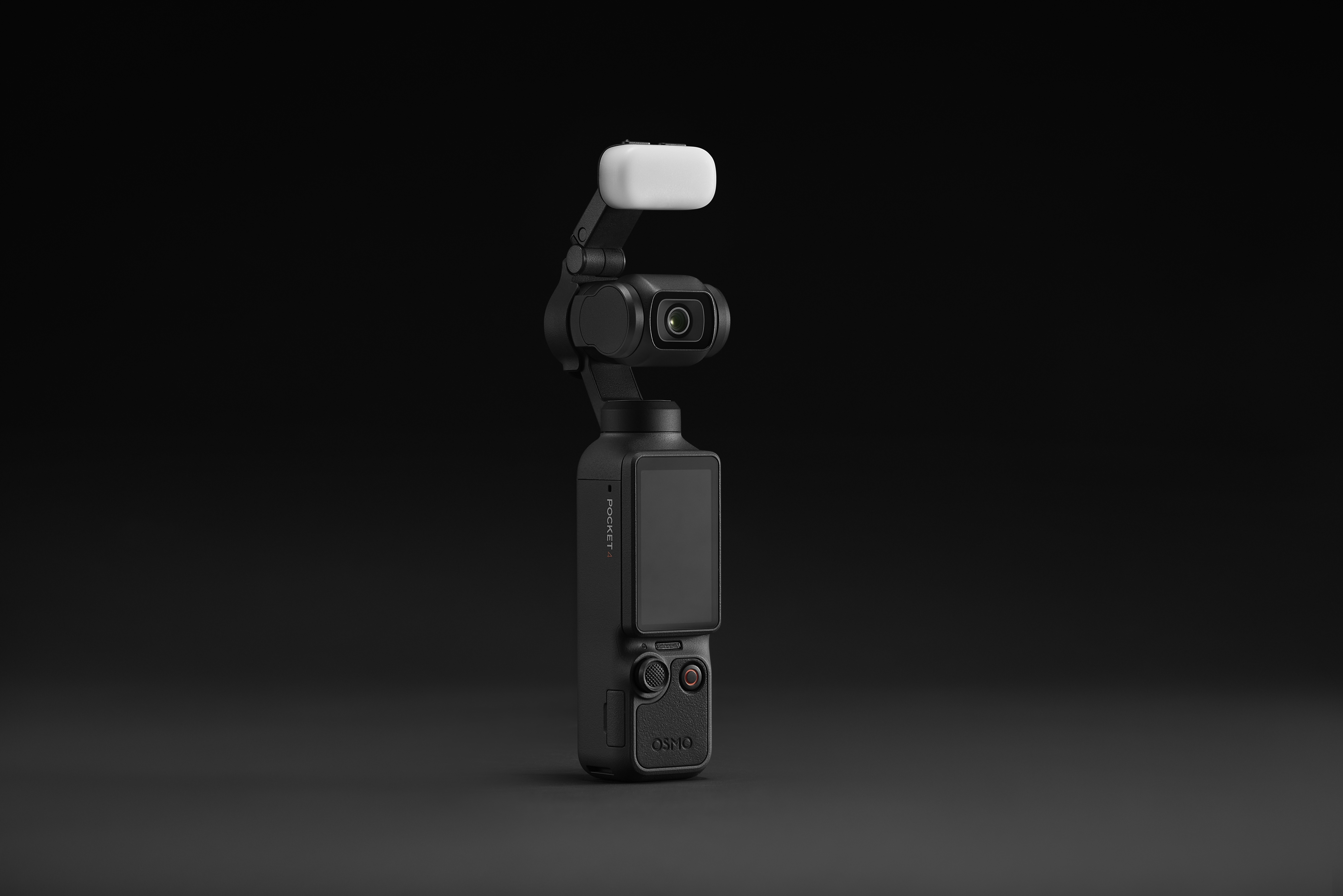 Ein schwarzer Gimbal mit Kamera, Bildschirm und weißem Licht auf dunklem Hintergrund.
