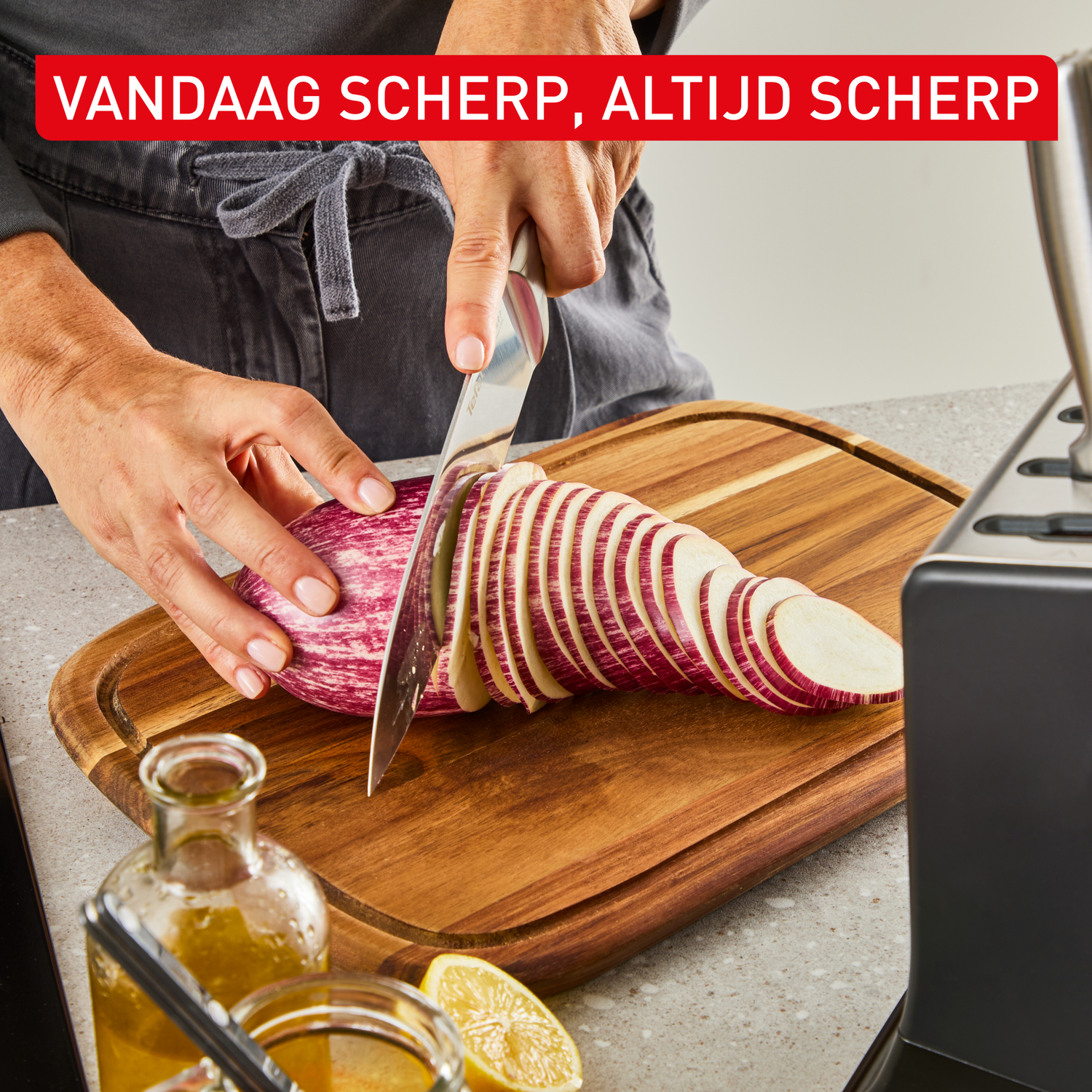 Een persoon snijdt een aubergine in plakjes op een houten snijplank.