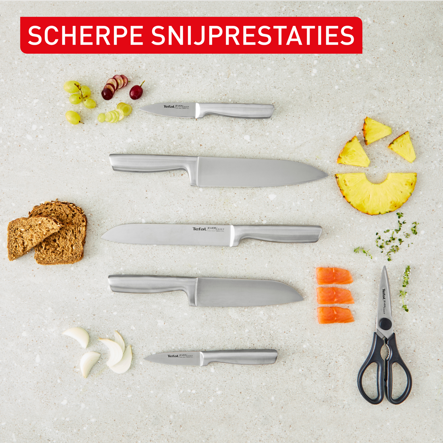 Messen, brood, knoflook, druiven, ananas en kruiden op een stenen ondergrond.
