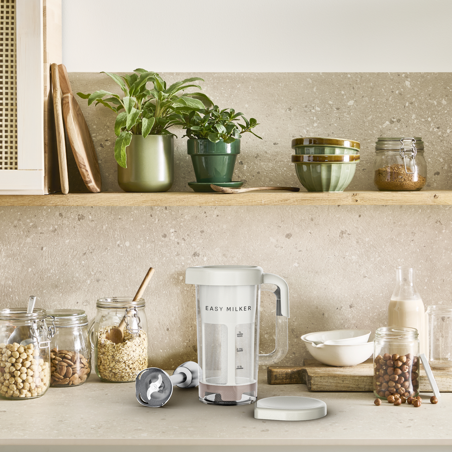 Keuken aanrecht met potten, een melkmachine, kommen en planten op een plank.