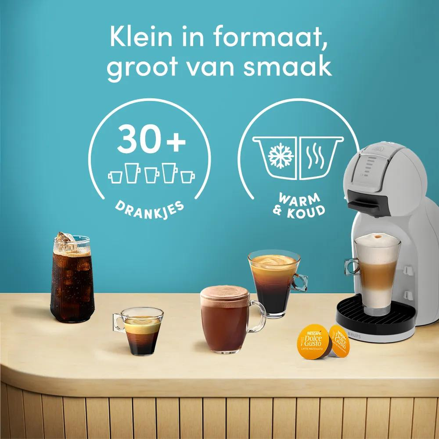 Een witte koffiemachine met diverse dranken en capsules op een houten tafel.