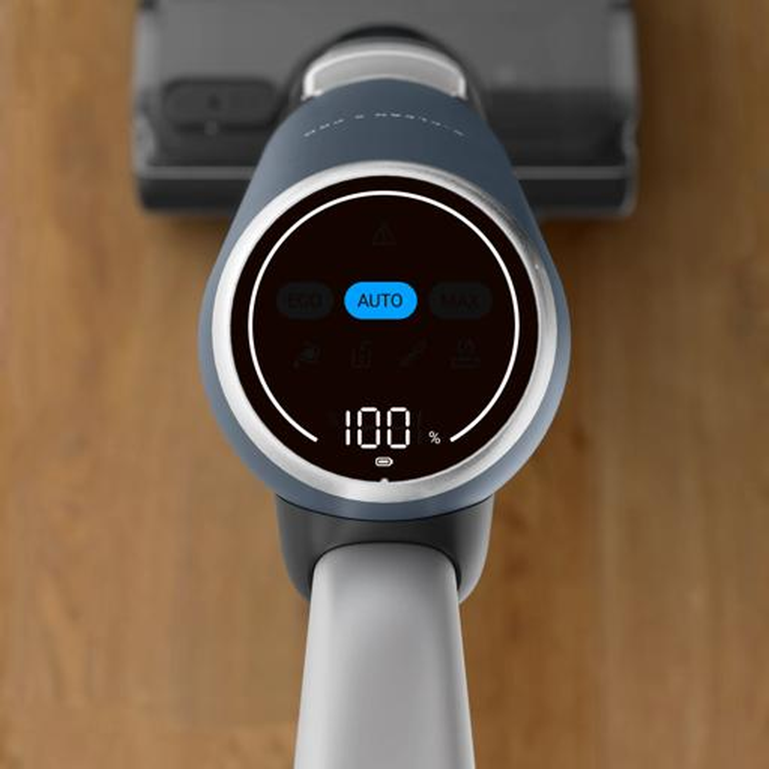Close-up of a cordless vacuum cleaner handle with a digital display showing 100% battery.