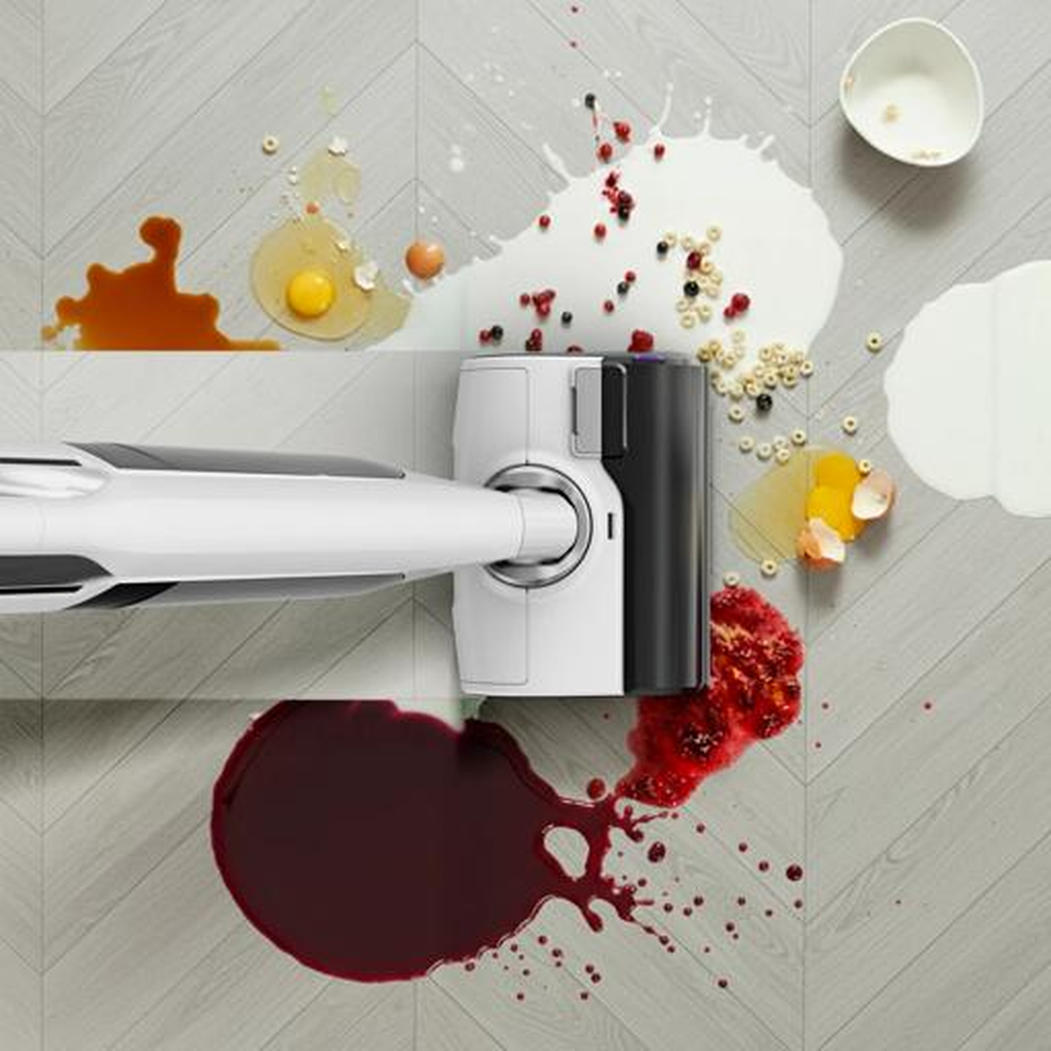 A vacuum cleaner cleans up spills of liquid and food on a wood floor.