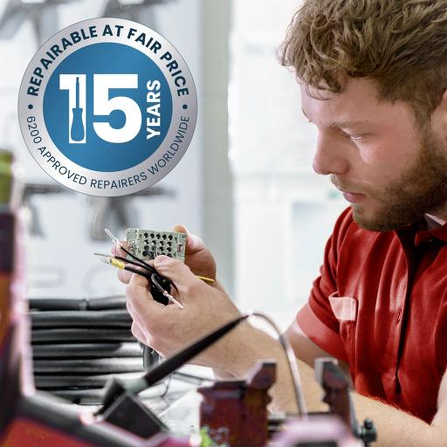 Een man in een rood shirt repareert een elektrische component met draden.