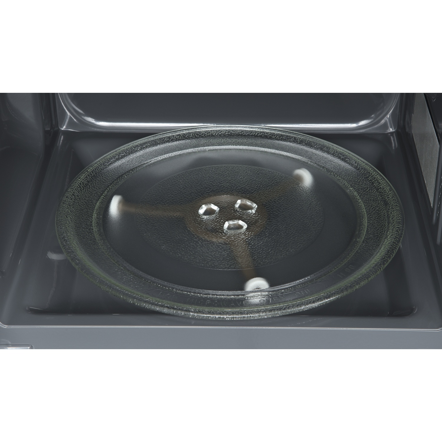 Un piatto girevole rotondo in vetro con tre rulli argentati all'interno di un forno a microonde scuro.