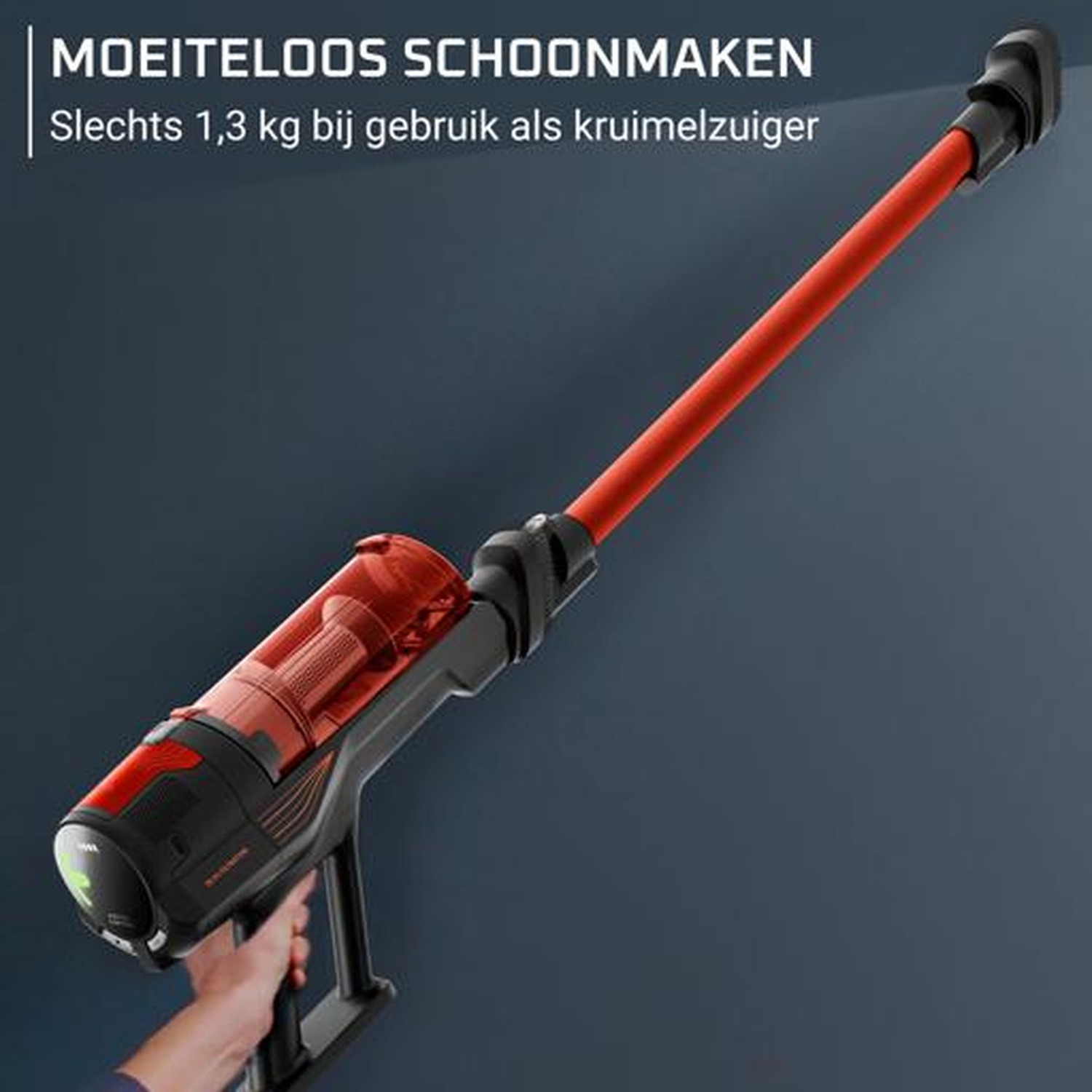 A red and black cordless vacuum cleaner held by a hand.