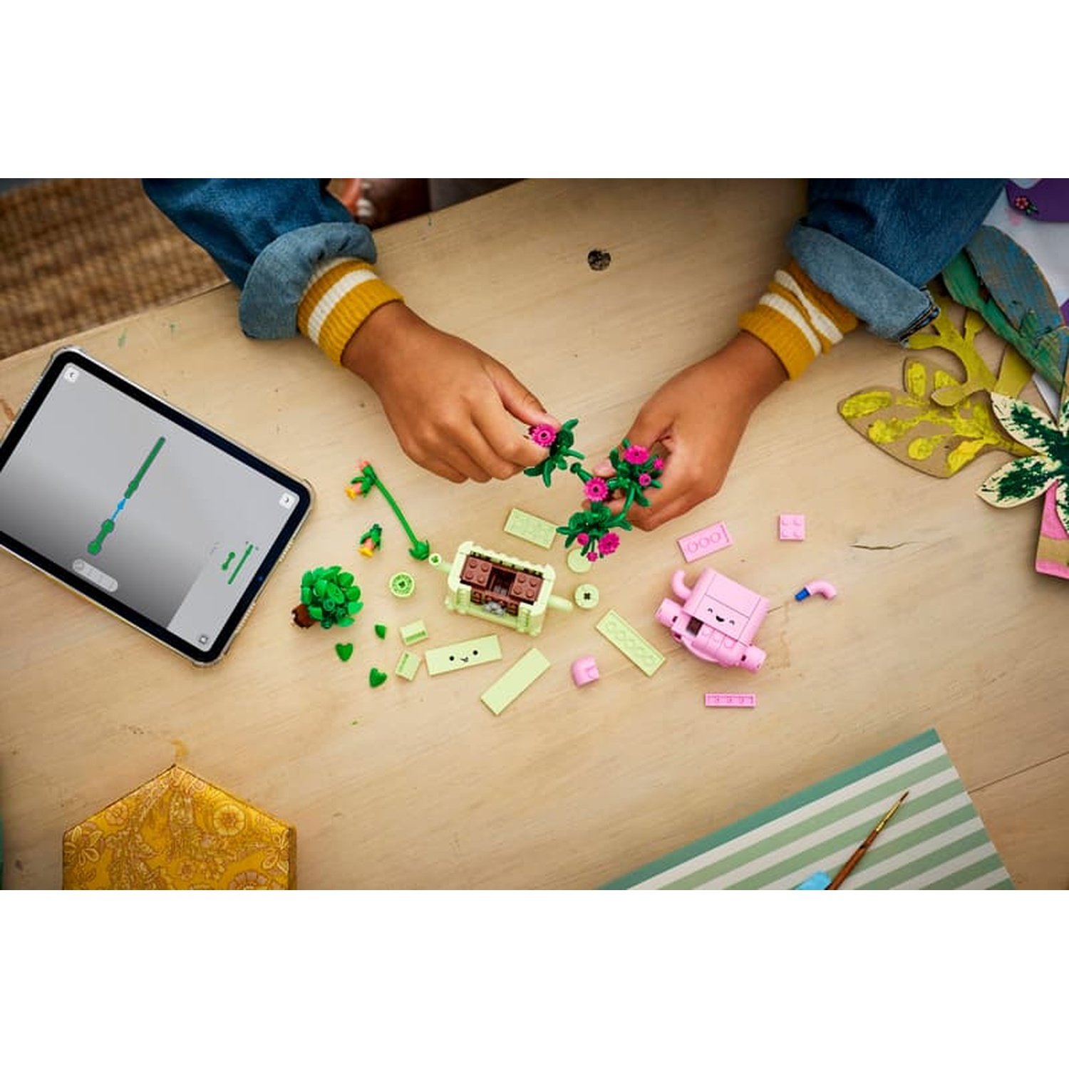 Bambino costruisce con Lego su tavolo di legno, istruzioni su tablet.