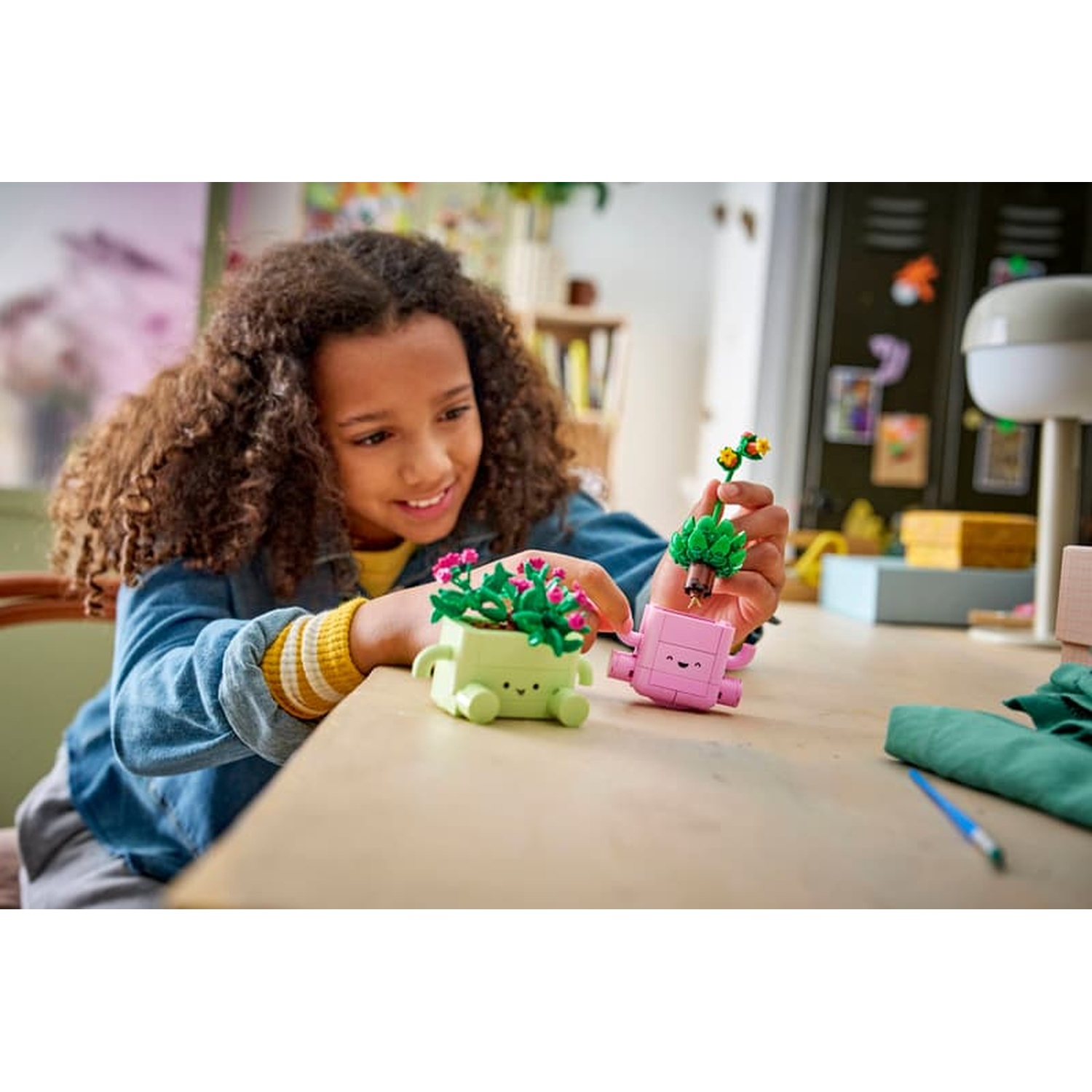 Una ragazza con i capelli ricci costruisce piccole piante Lego su un tavolo.