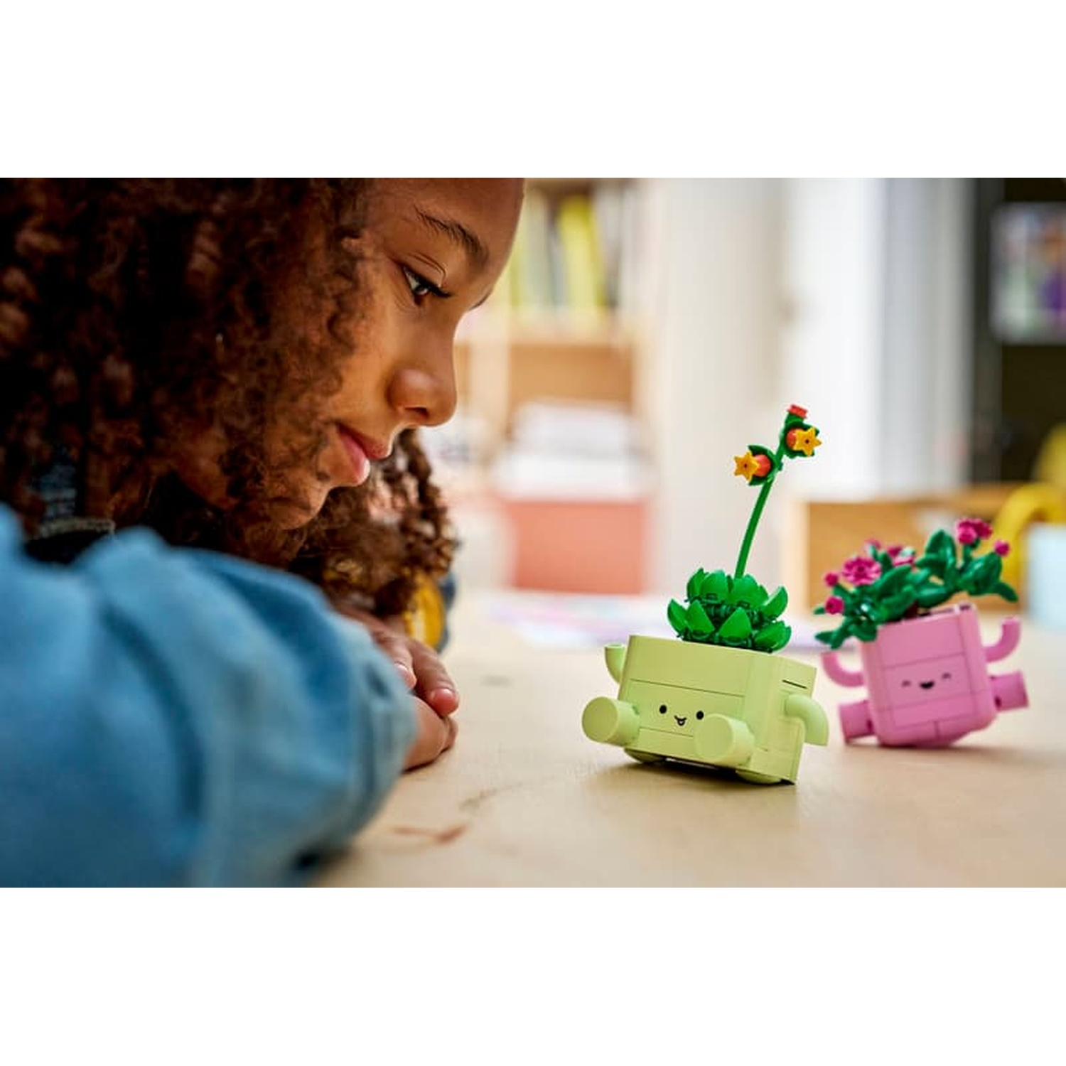 Una ragazza guarda due piccole piante LEGO, una verde e una rosa.
