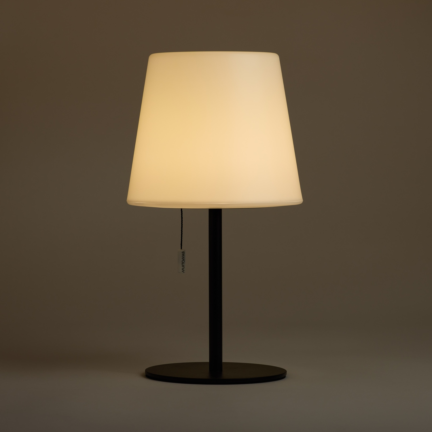 Una lampada bianca con base e stelo neri su sfondo marrone.