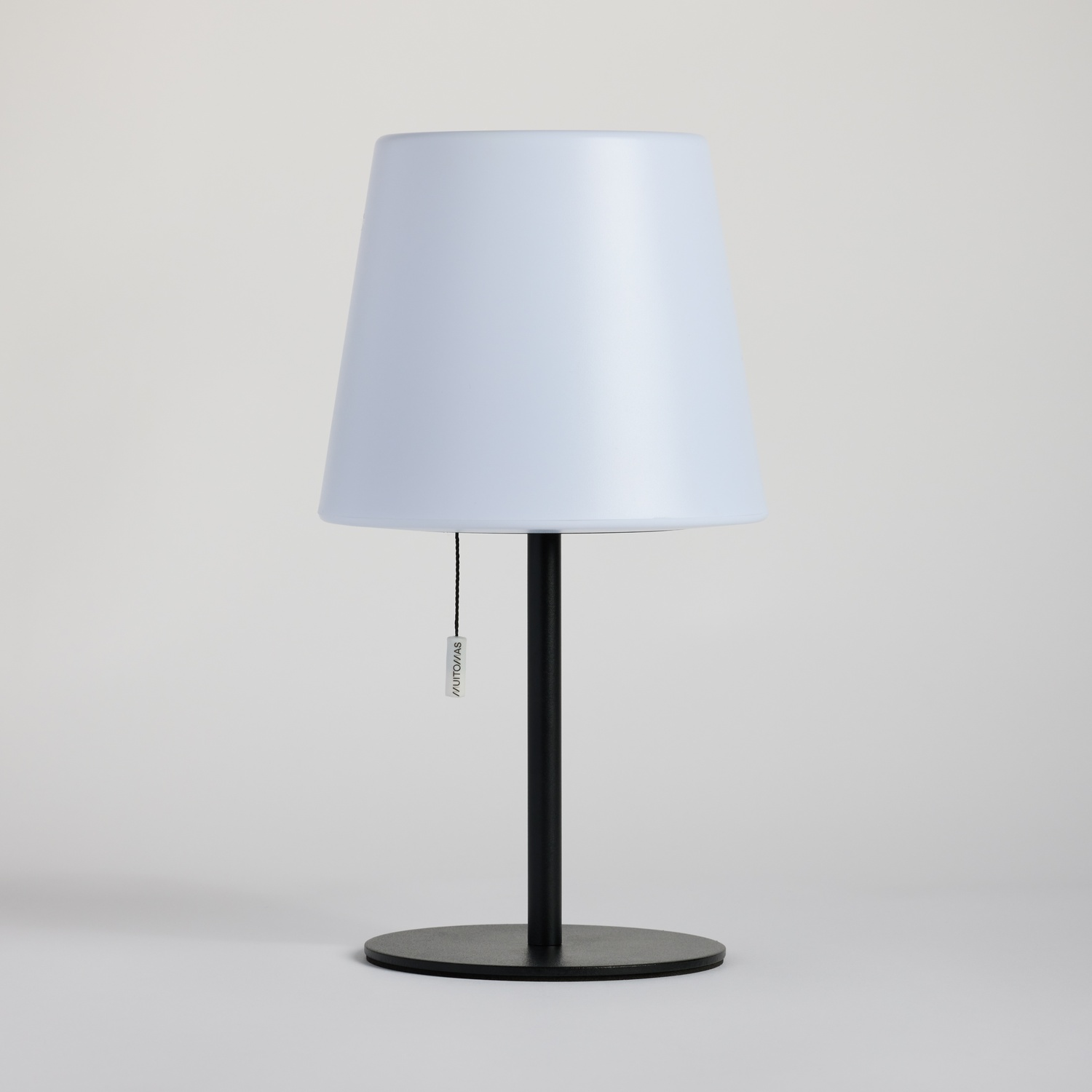 Una lampada da terra nera con paralume conico bianco e base rotonda.