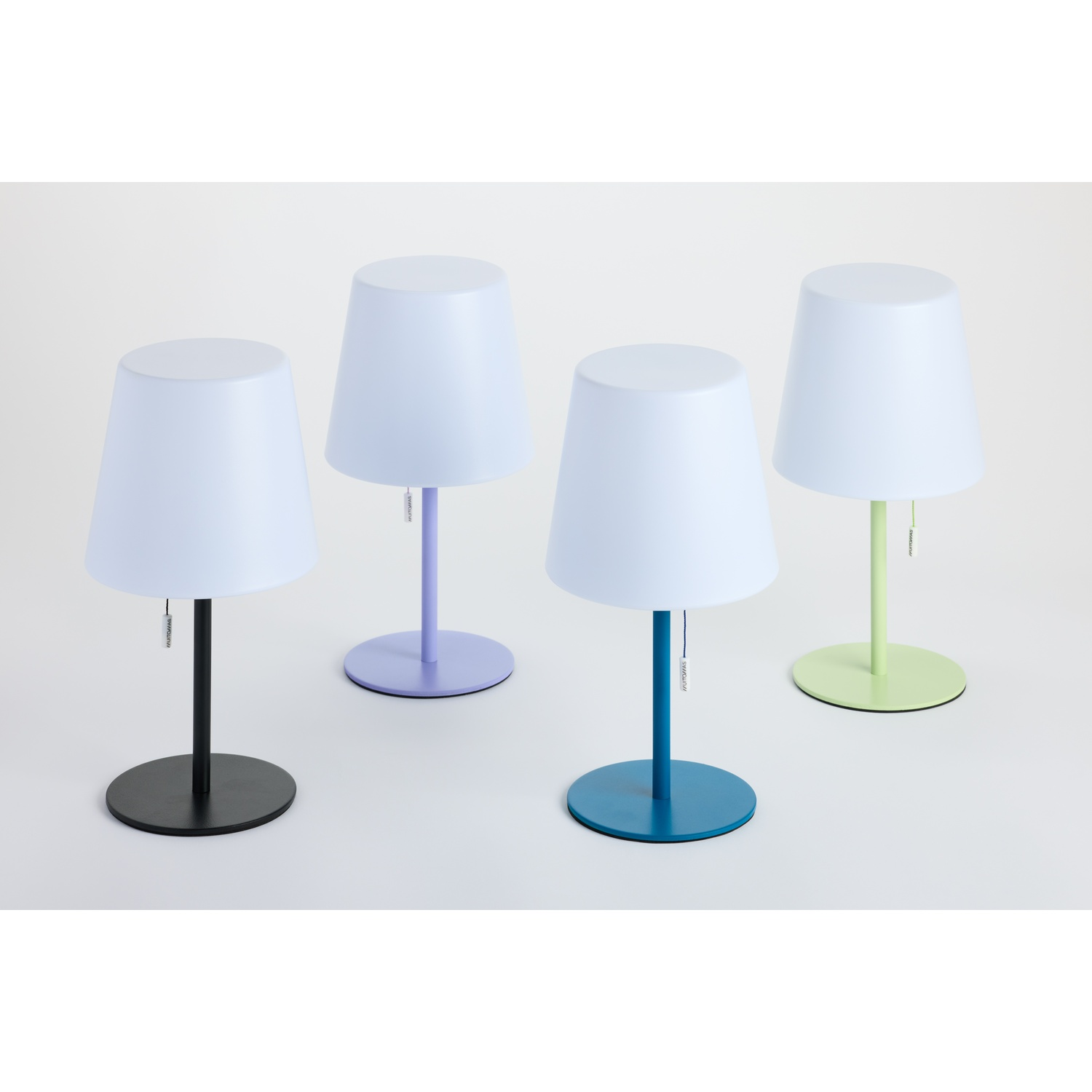 Quattro lampade moderne con paralumi bianchi e basi colorate: nero, viola, blu e verde.