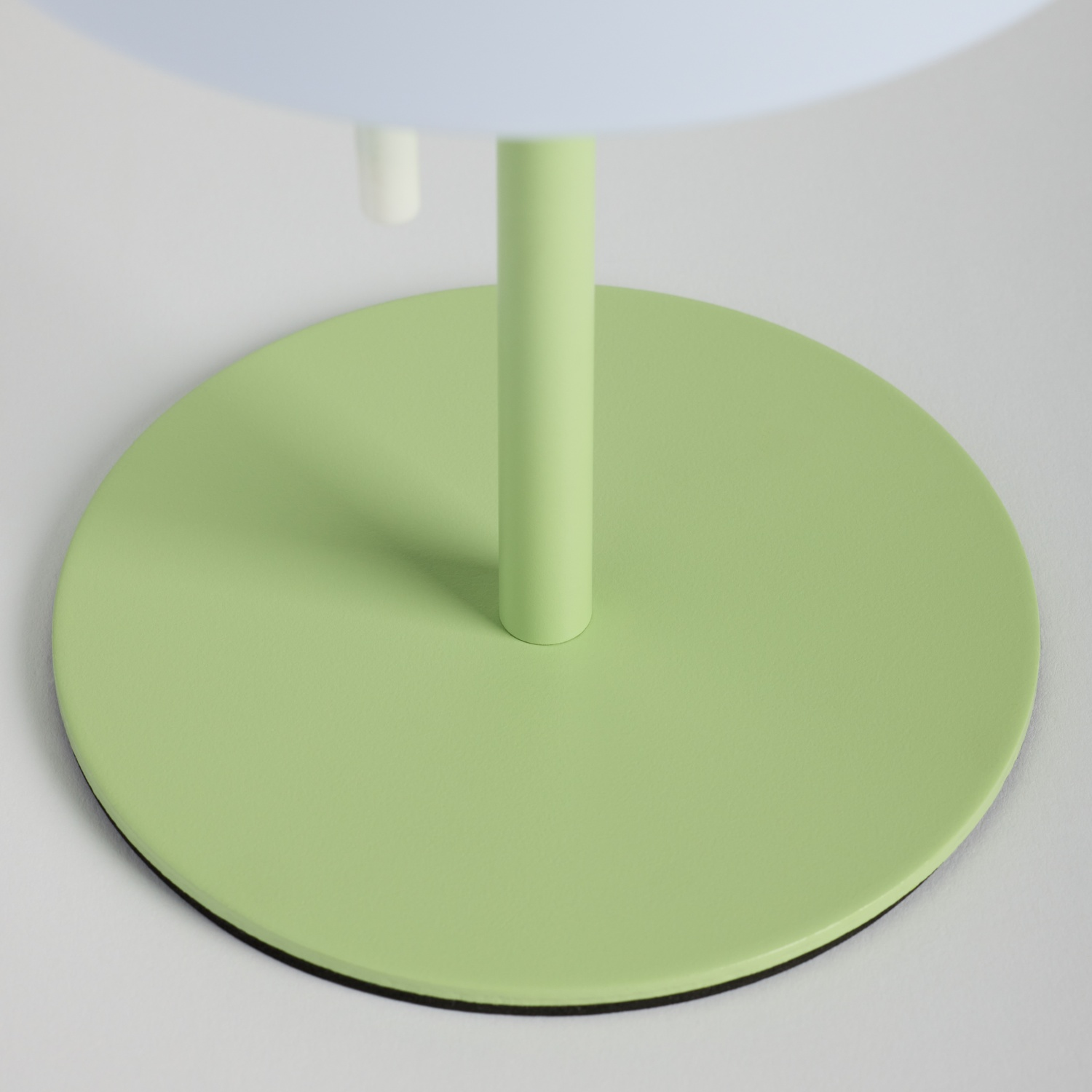 Una base rotonda verde chiaro con un supporto snello verde chiaro.