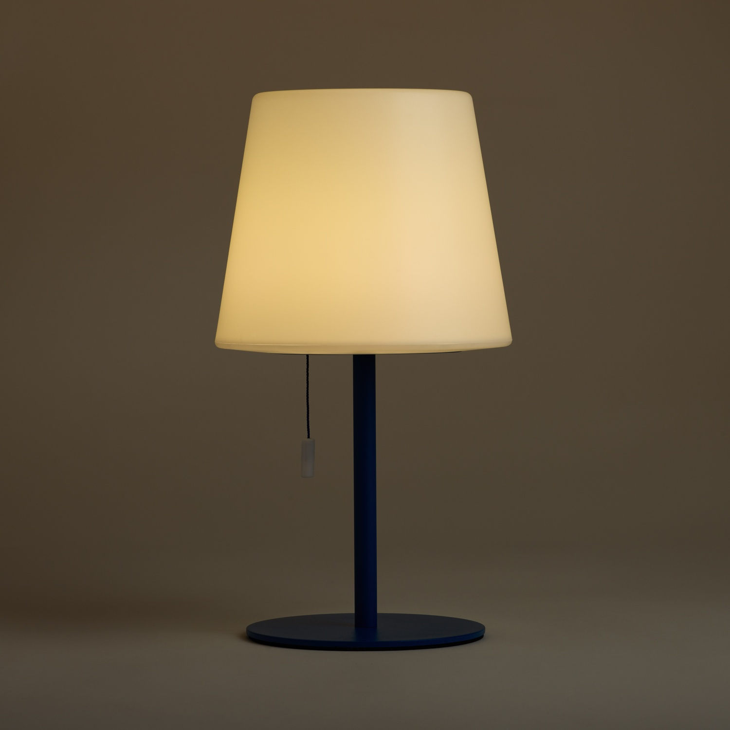 Una lampada da tavolo con paralume bianco e base blu.